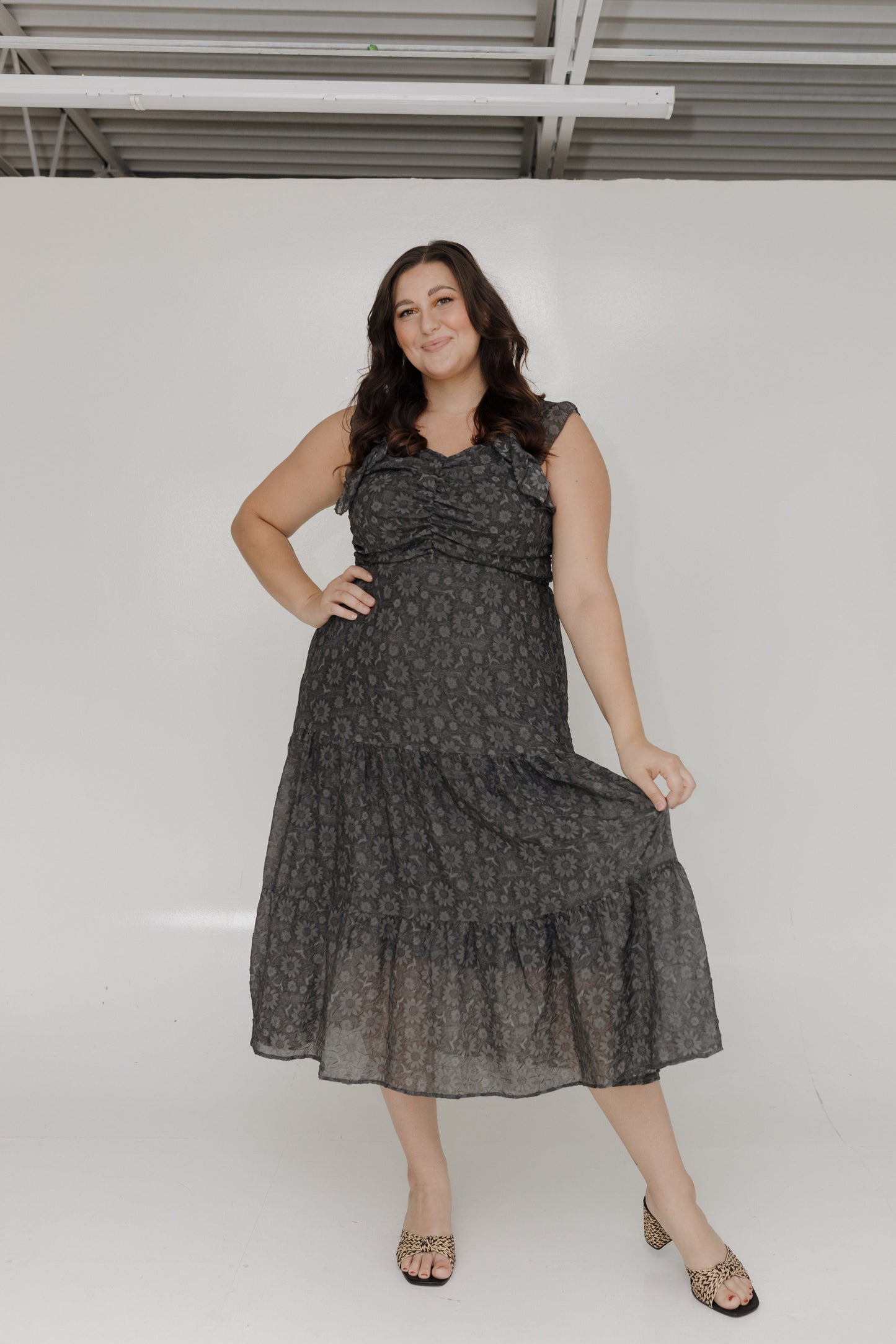 Woman wearing a black patterned dress against a white background