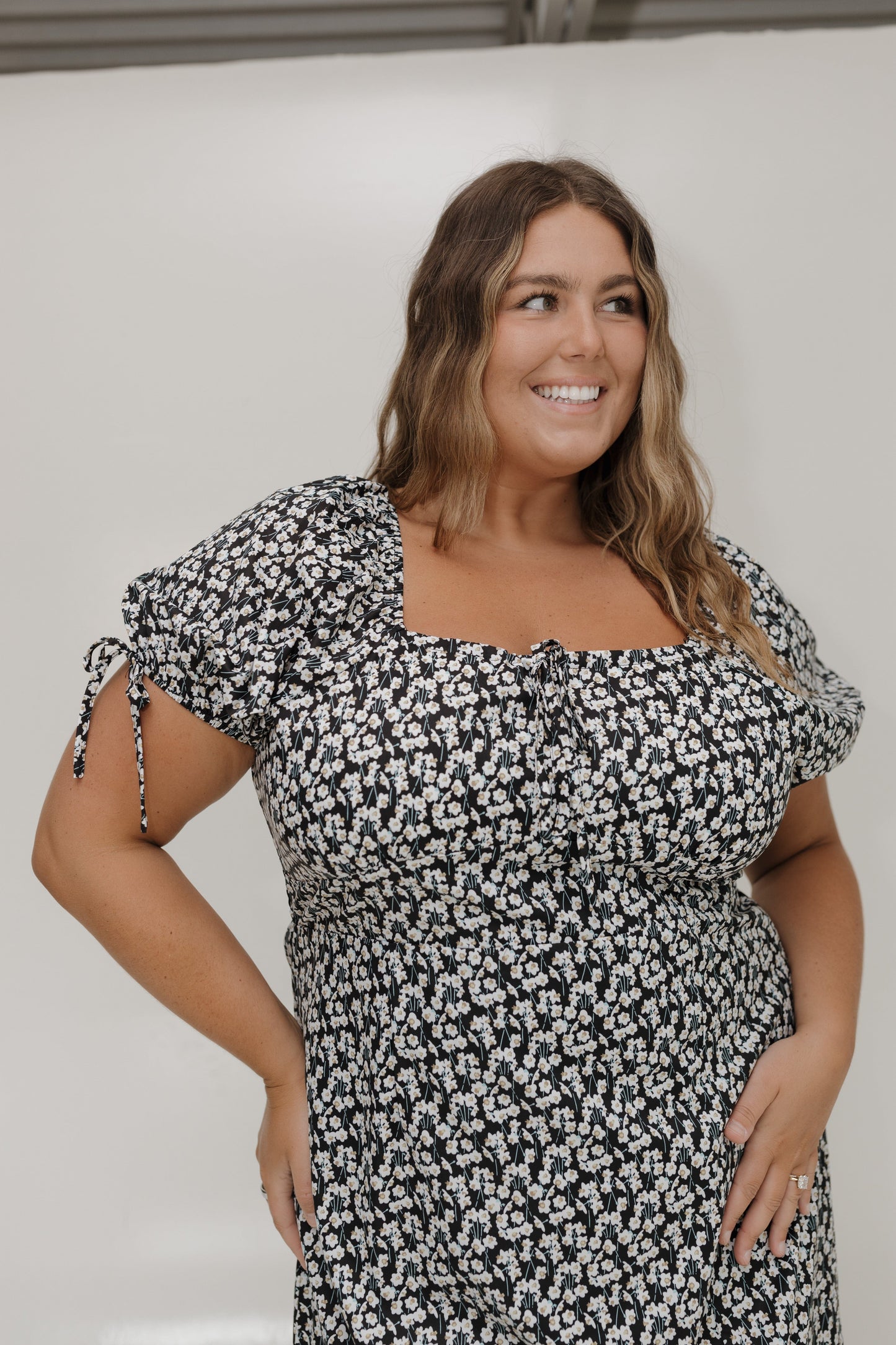 Woman wearing a black and white floral dress against a plain background