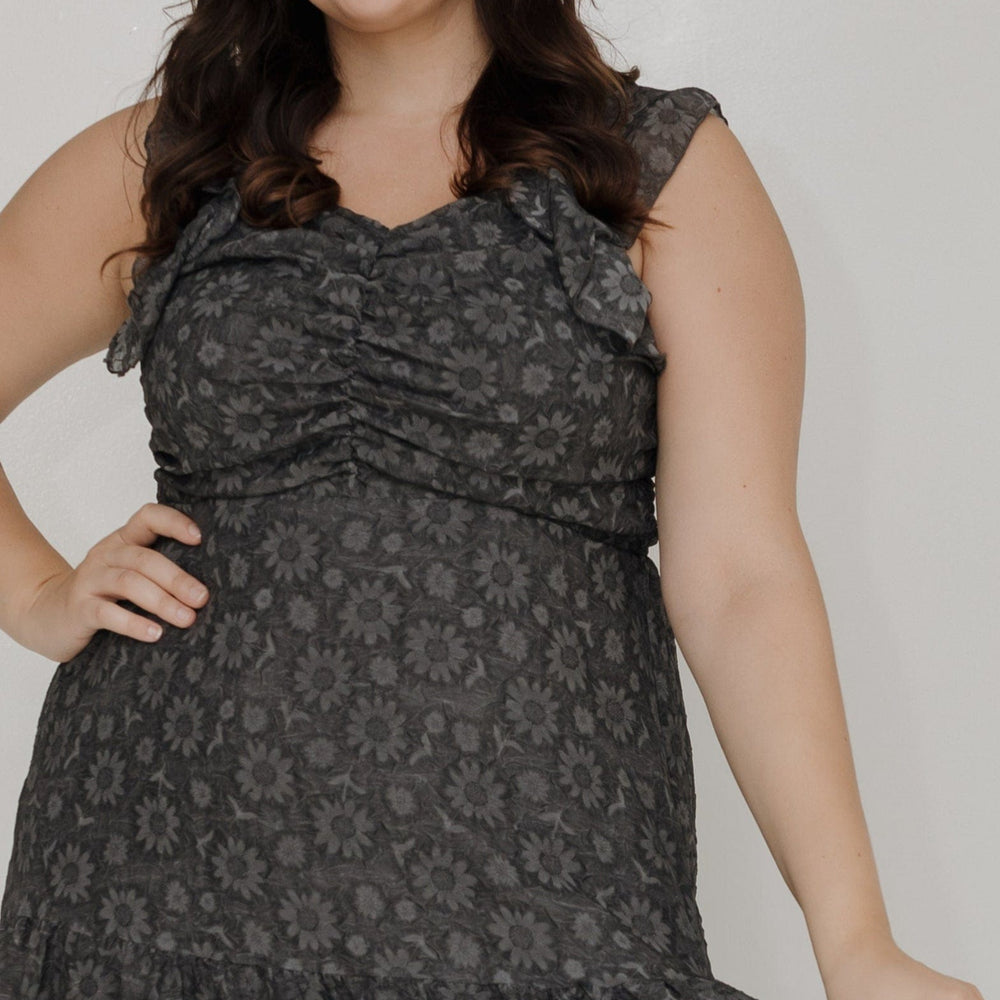 Woman wearing a black patterned dress against a white background