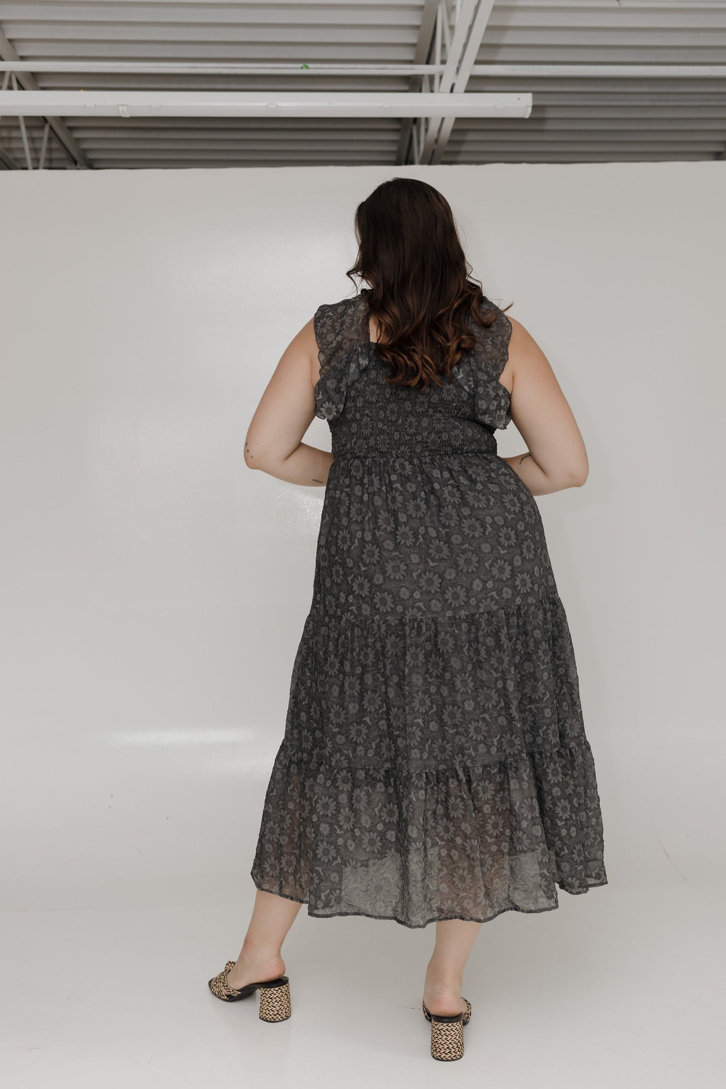 Woman wearing a dark patterned dress against a white wall