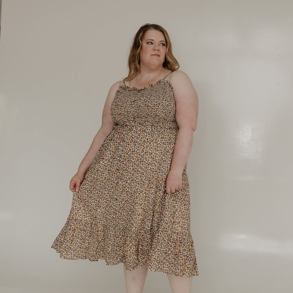 Woman wearing a patterned dress standing against a plain white background