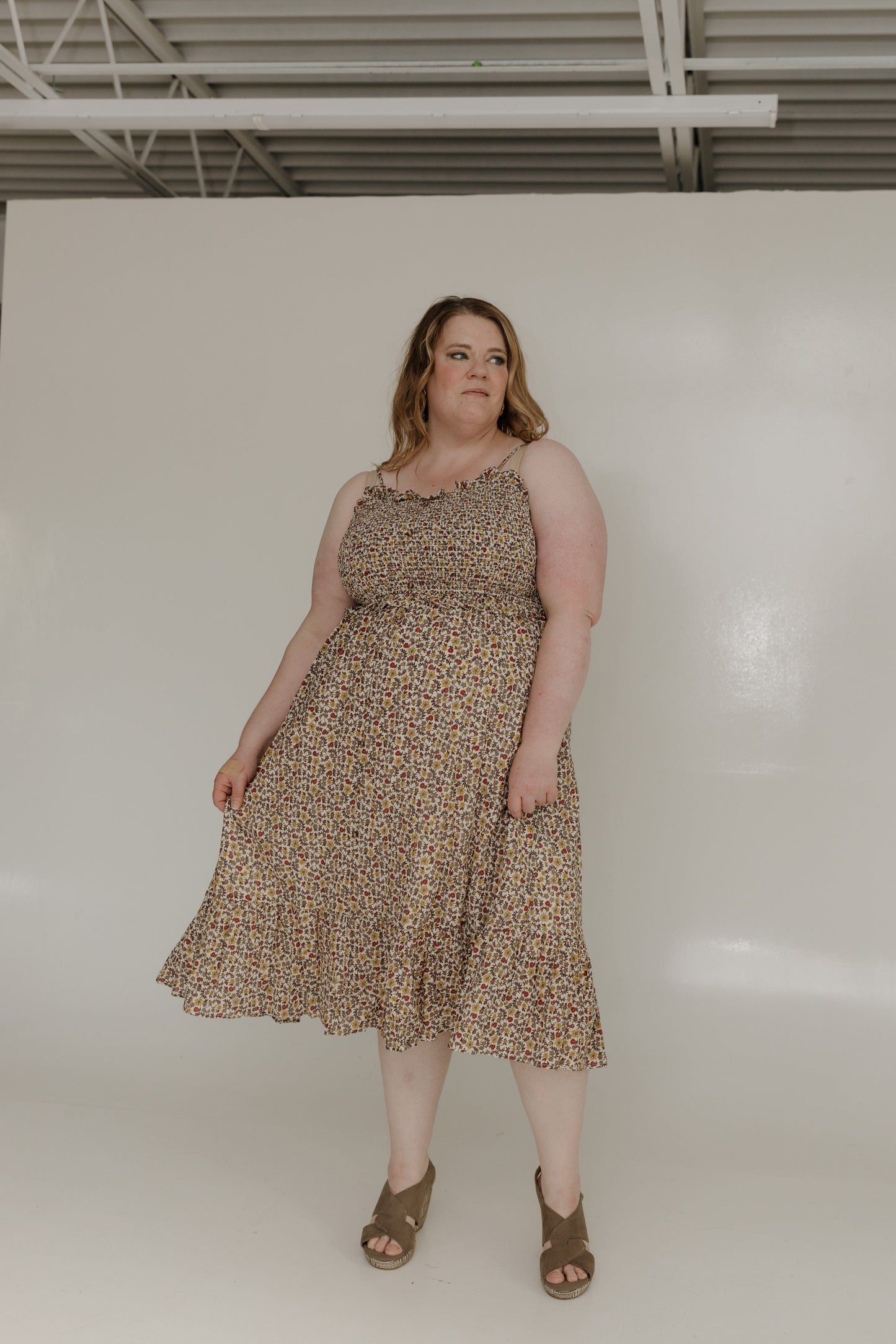 Woman wearing a patterned dress standing against a plain white background