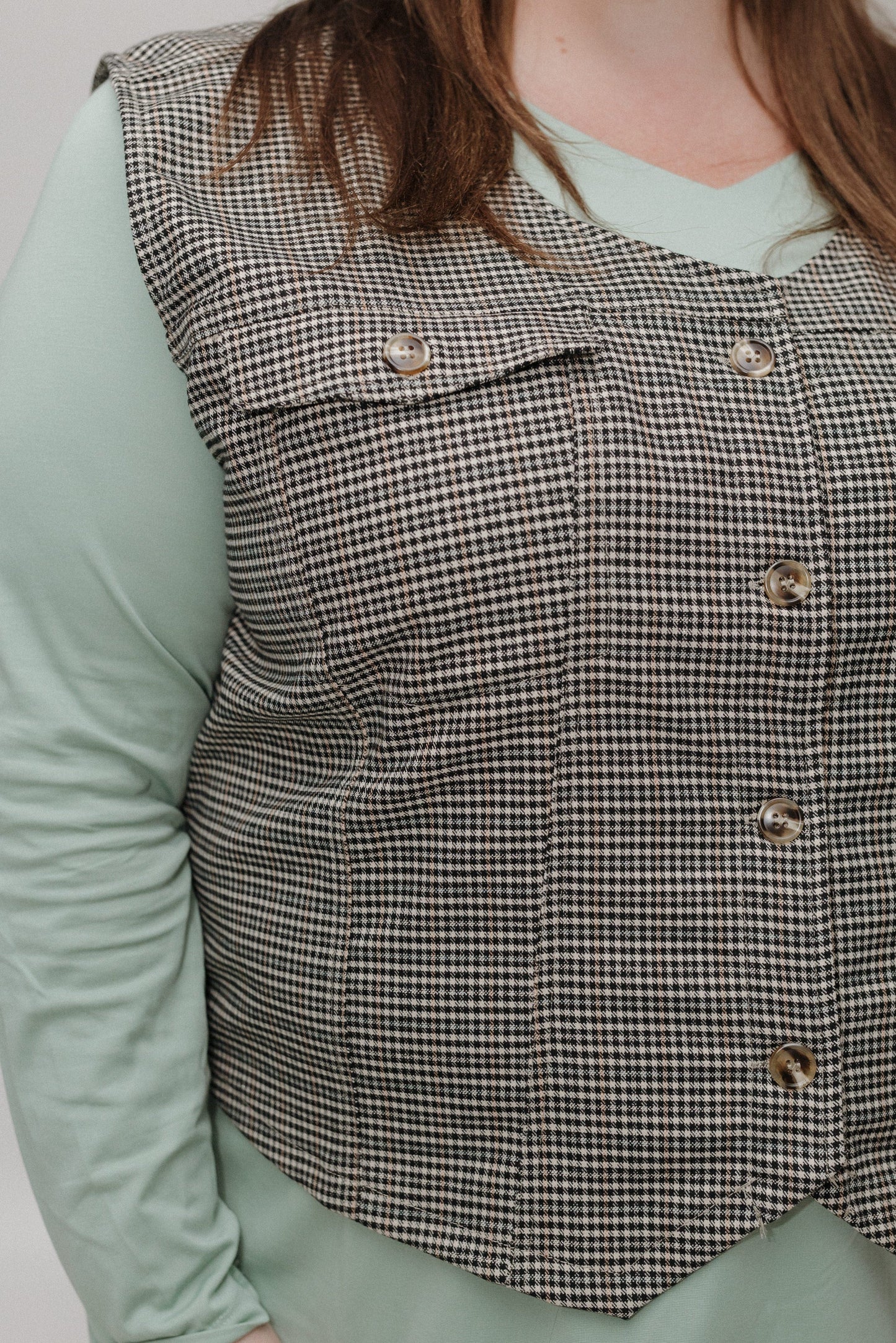Houndstooth patterned vest worn by a person with a light green shirt underneath.