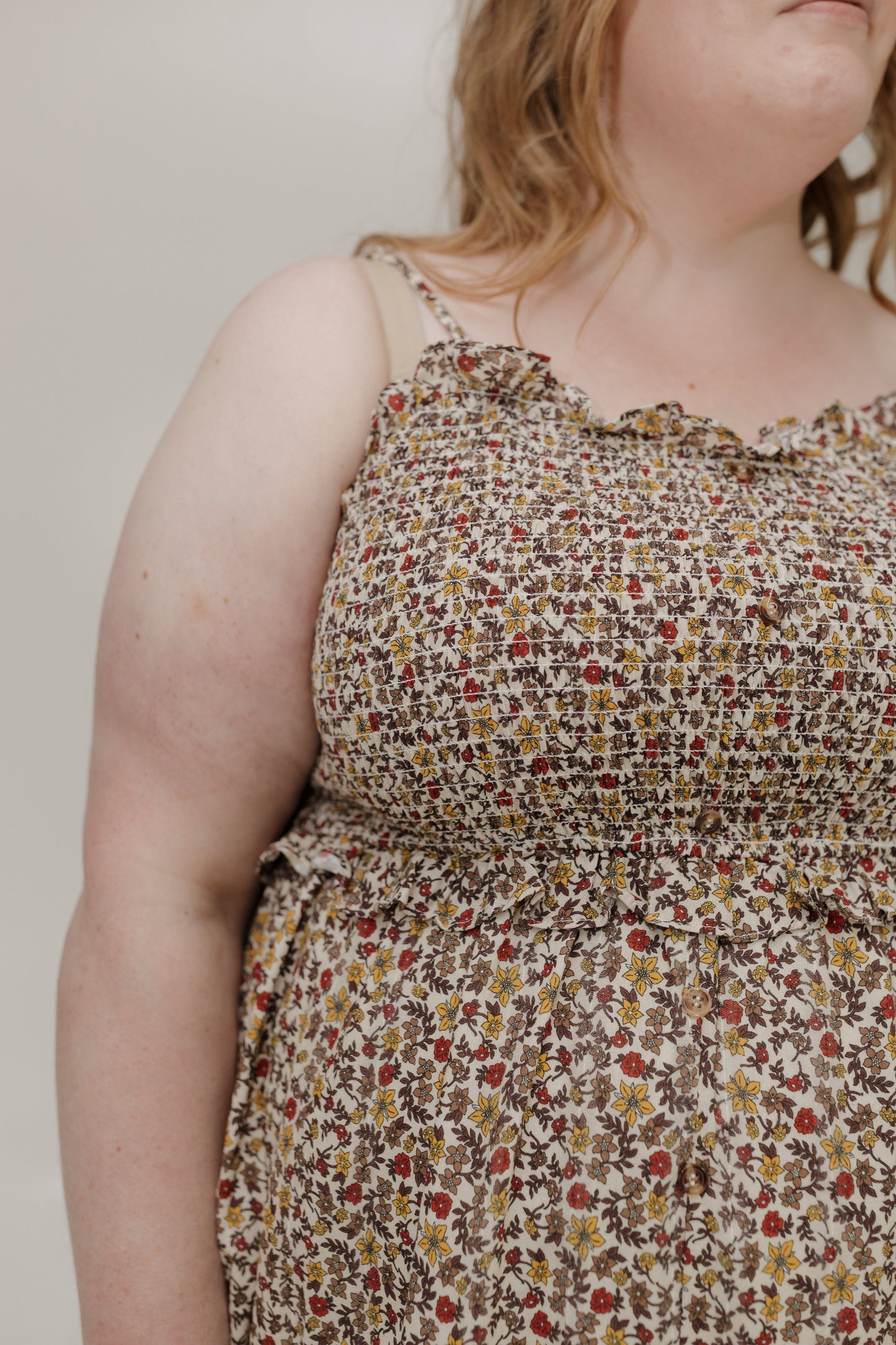 Person wearing a floral dress with a neutral background
