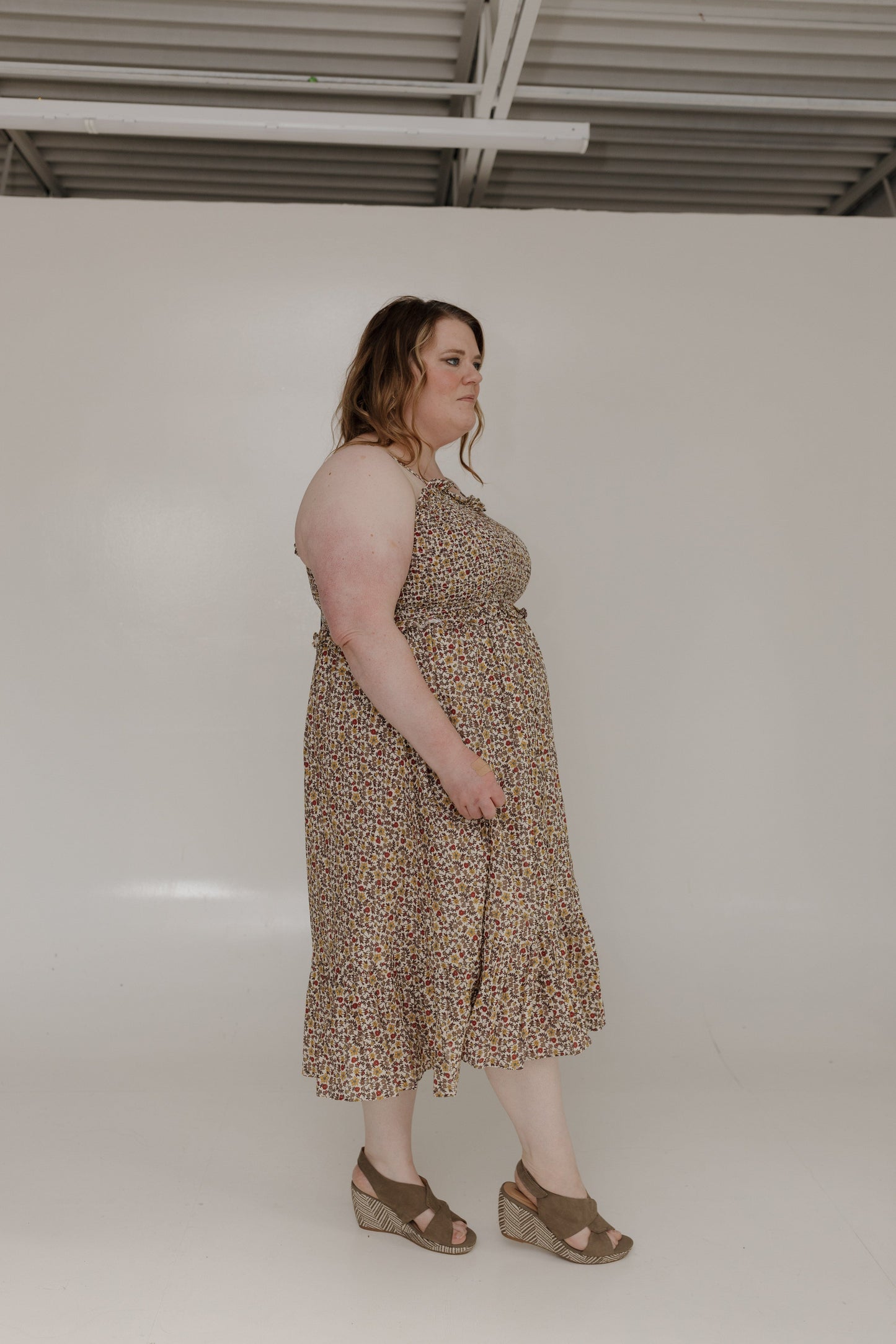 Woman wearing a patterned dress standing against a plain white background