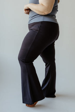 A person wearing the ultra-flattering FLARE TREGGING IN NAVY by Yesta and a gray top stands against a neutral background.