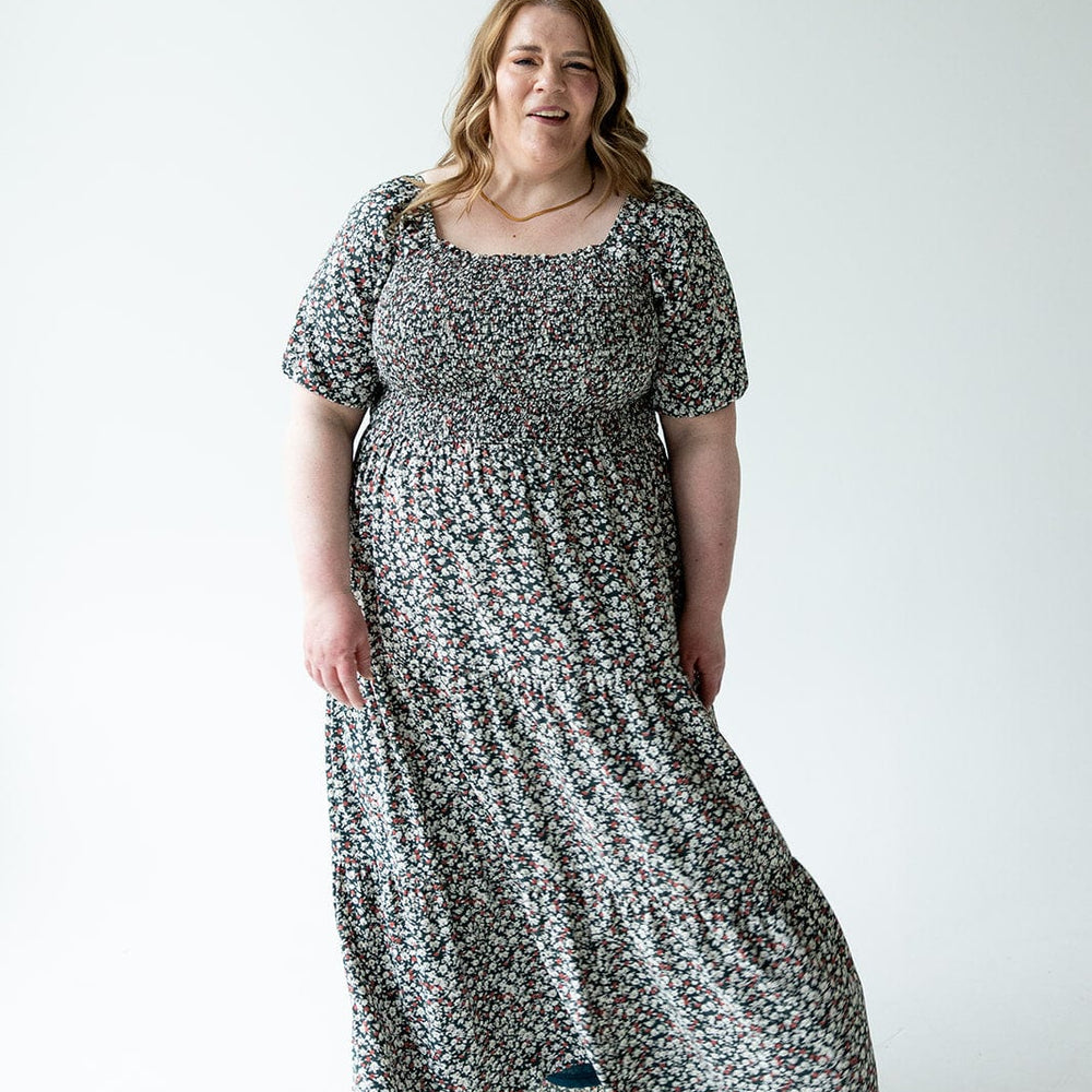 A person in a floral dress with bubble sleeves stands against a plain white background.