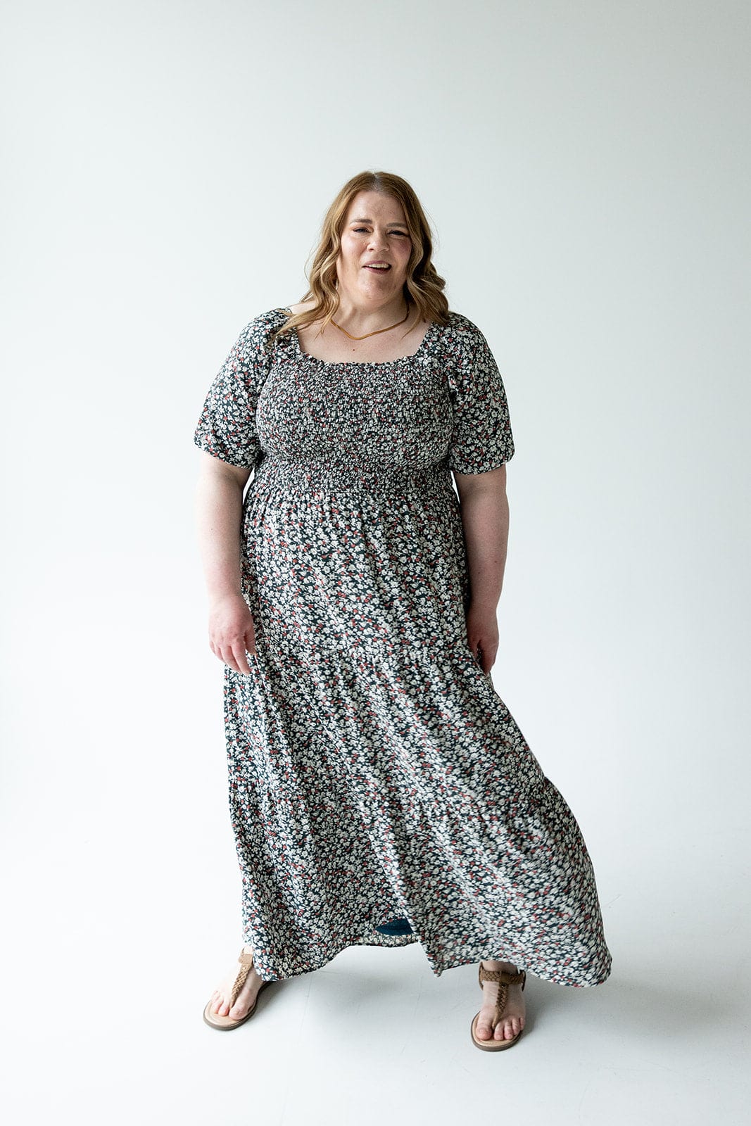 A person in a floral dress with bubble sleeves stands against a plain white background.