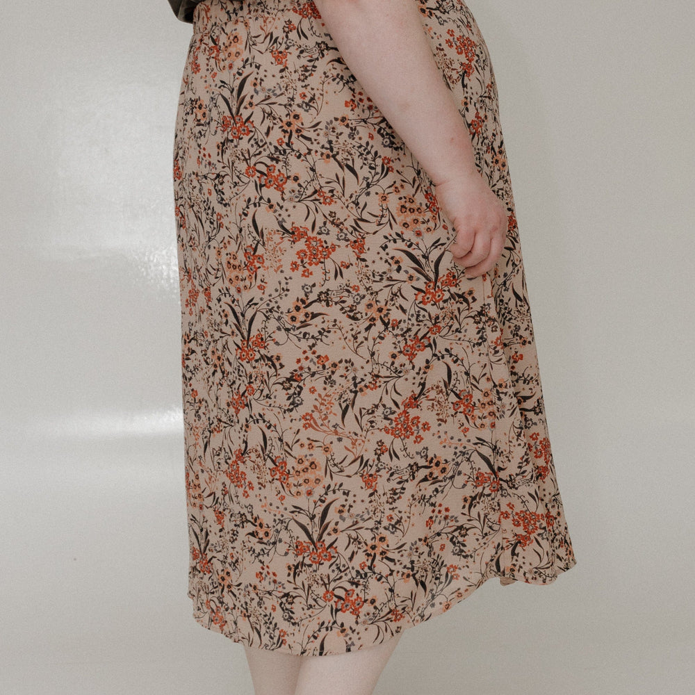 Person wearing a floral skirt with a plain background