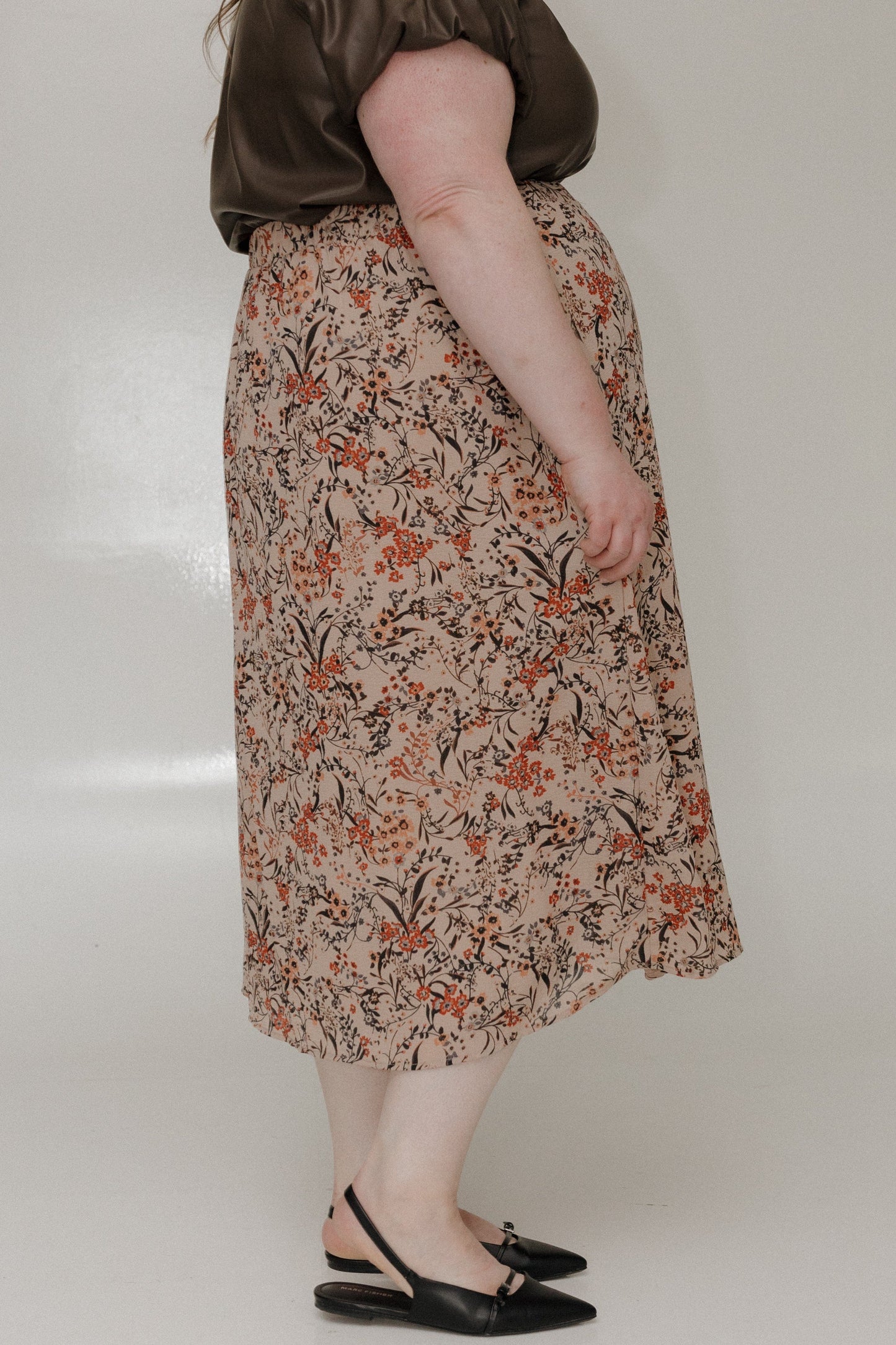 Person wearing a floral skirt with a plain background