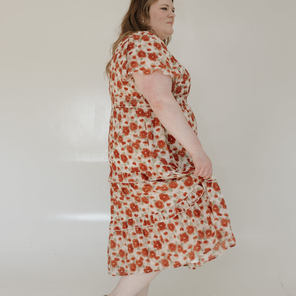 Woman wearing a floral dress standing against a white wall