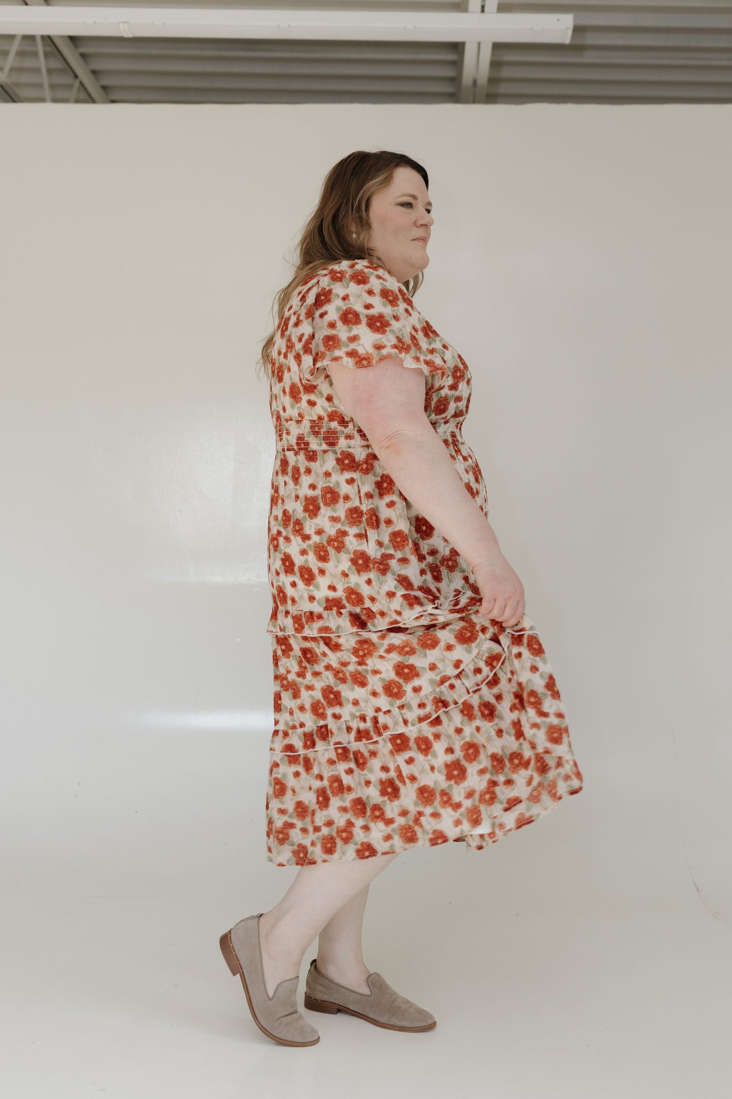 Woman wearing a floral dress standing against a white wall