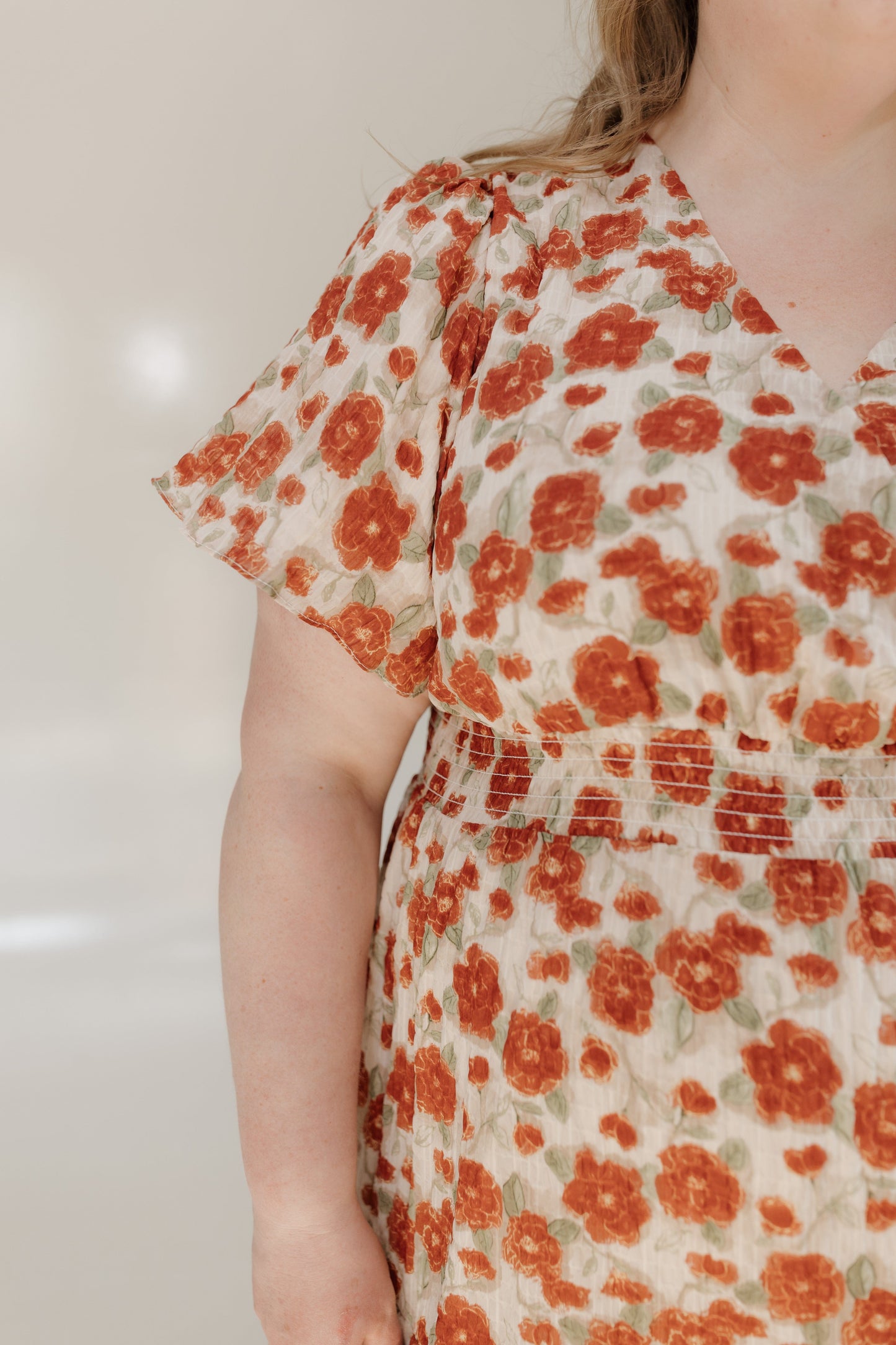 Person wearing a floral dress with red flowers on a plain background