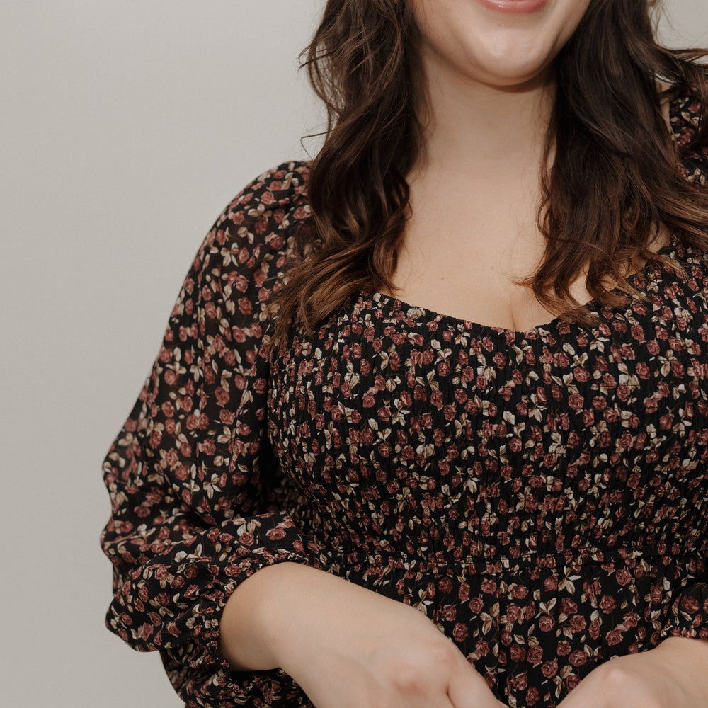 Woman wearing a floral dress against a plain background