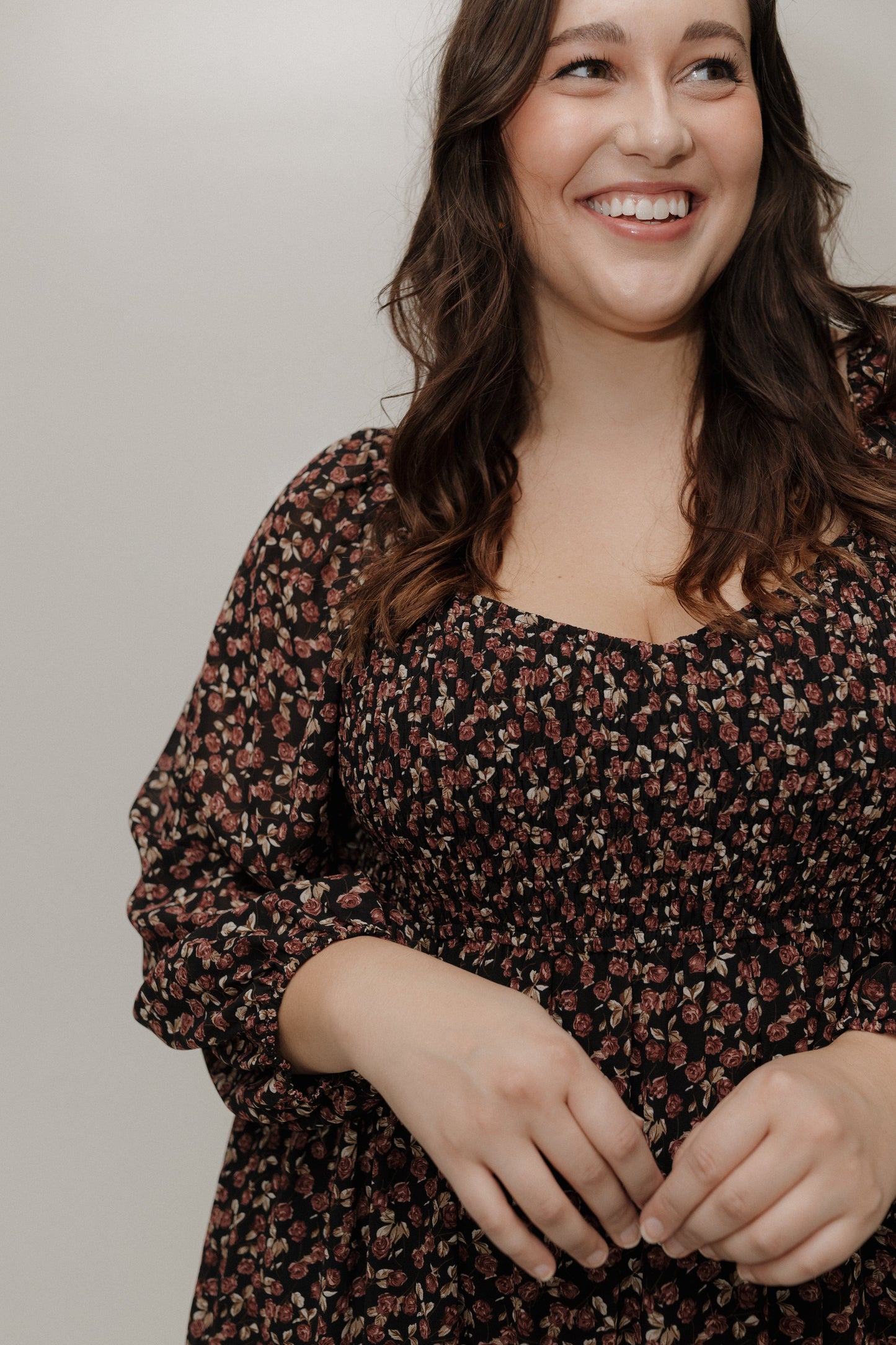 Woman wearing a floral dress against a plain background