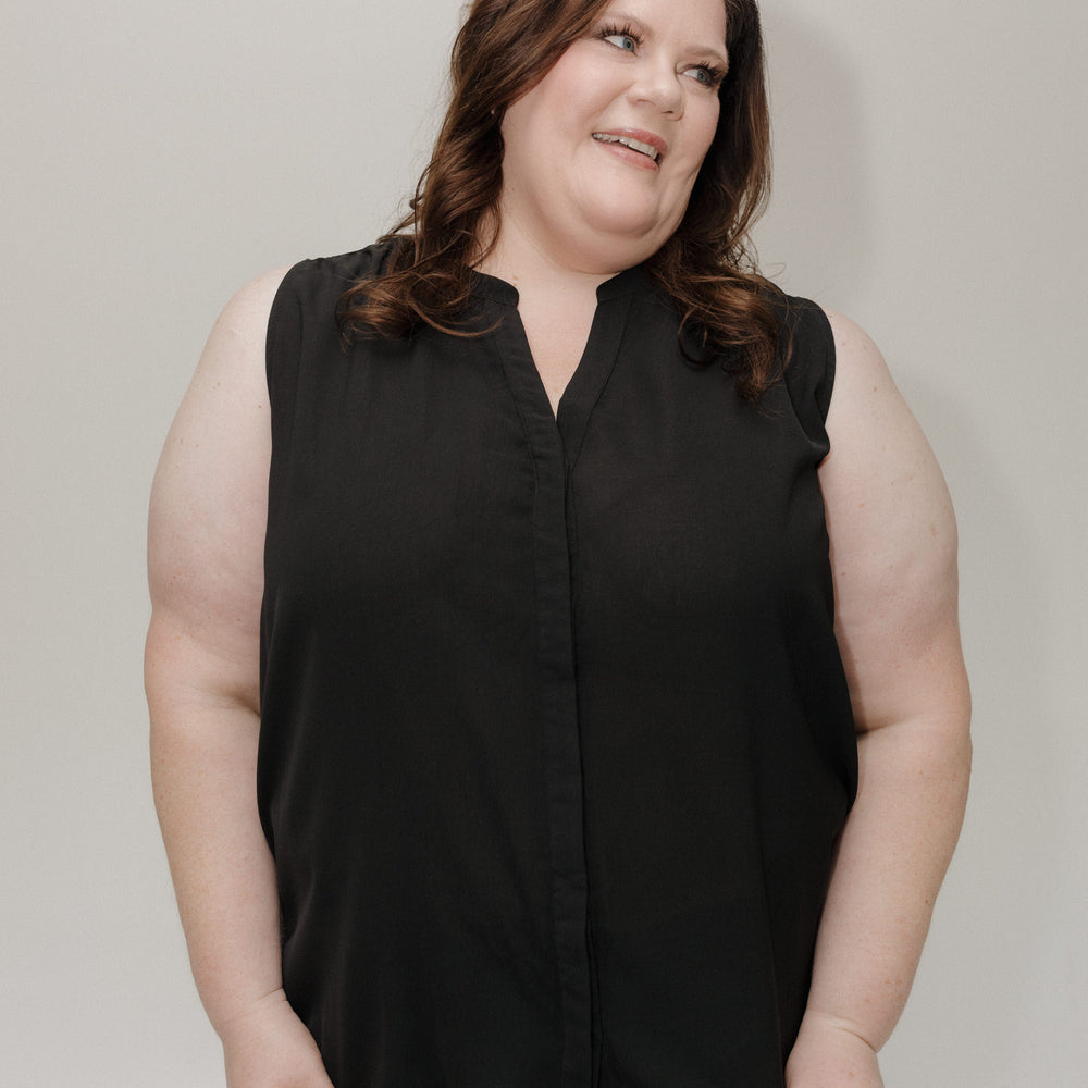 Person wearing a black sleeveless top against a plain background