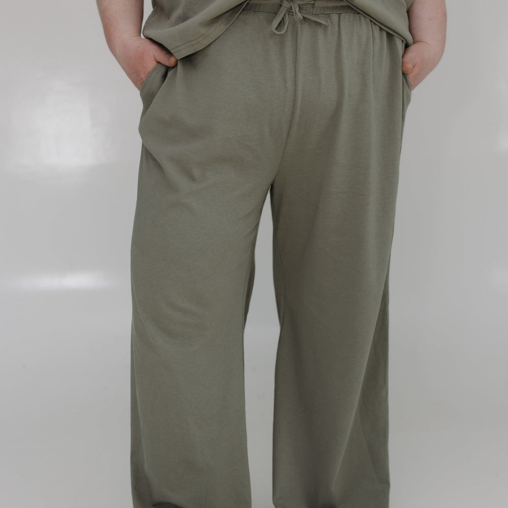 Person wearing olive green pants and shirt on a white background