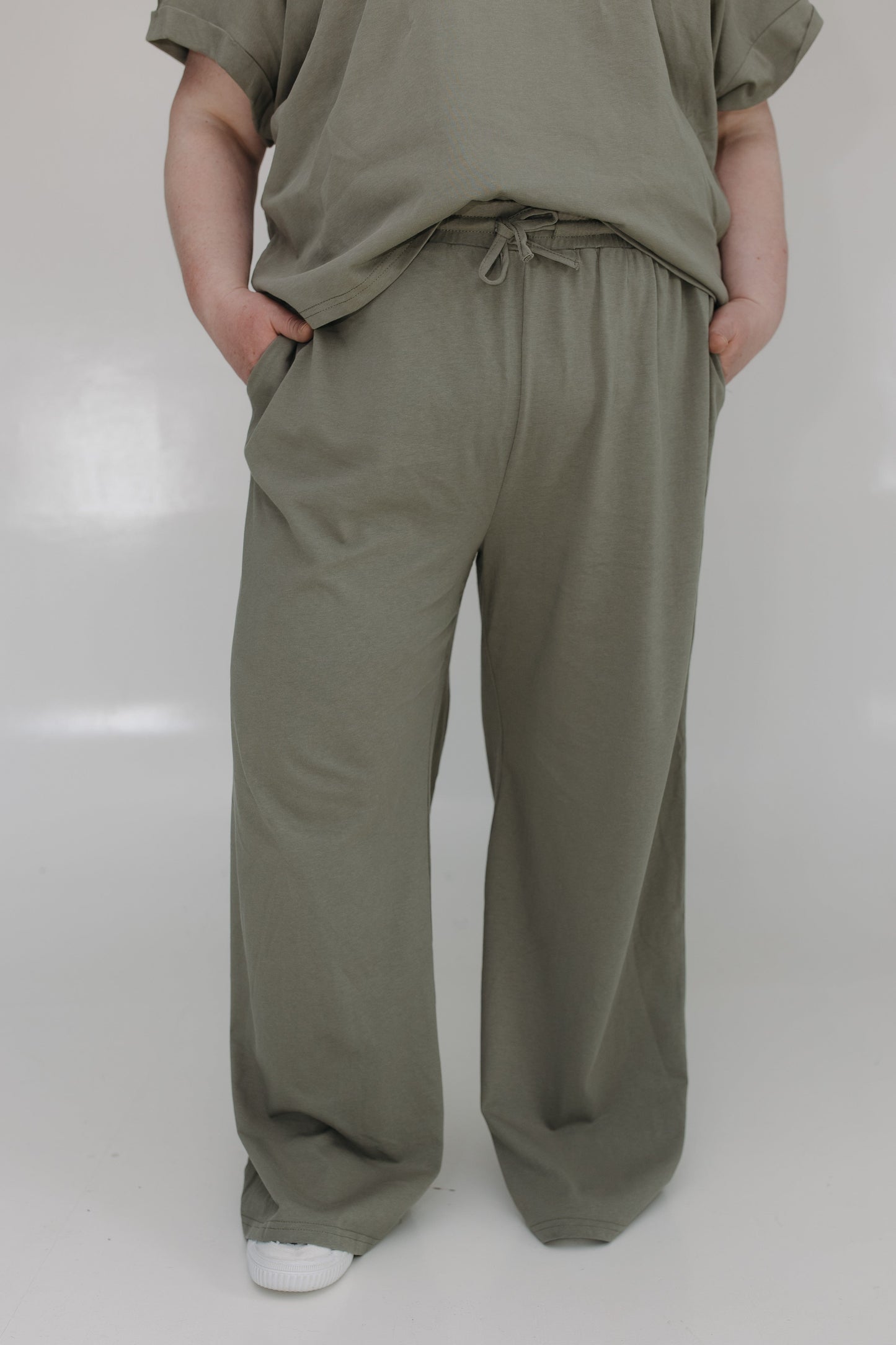 Person wearing olive green pants and shirt on a white background
