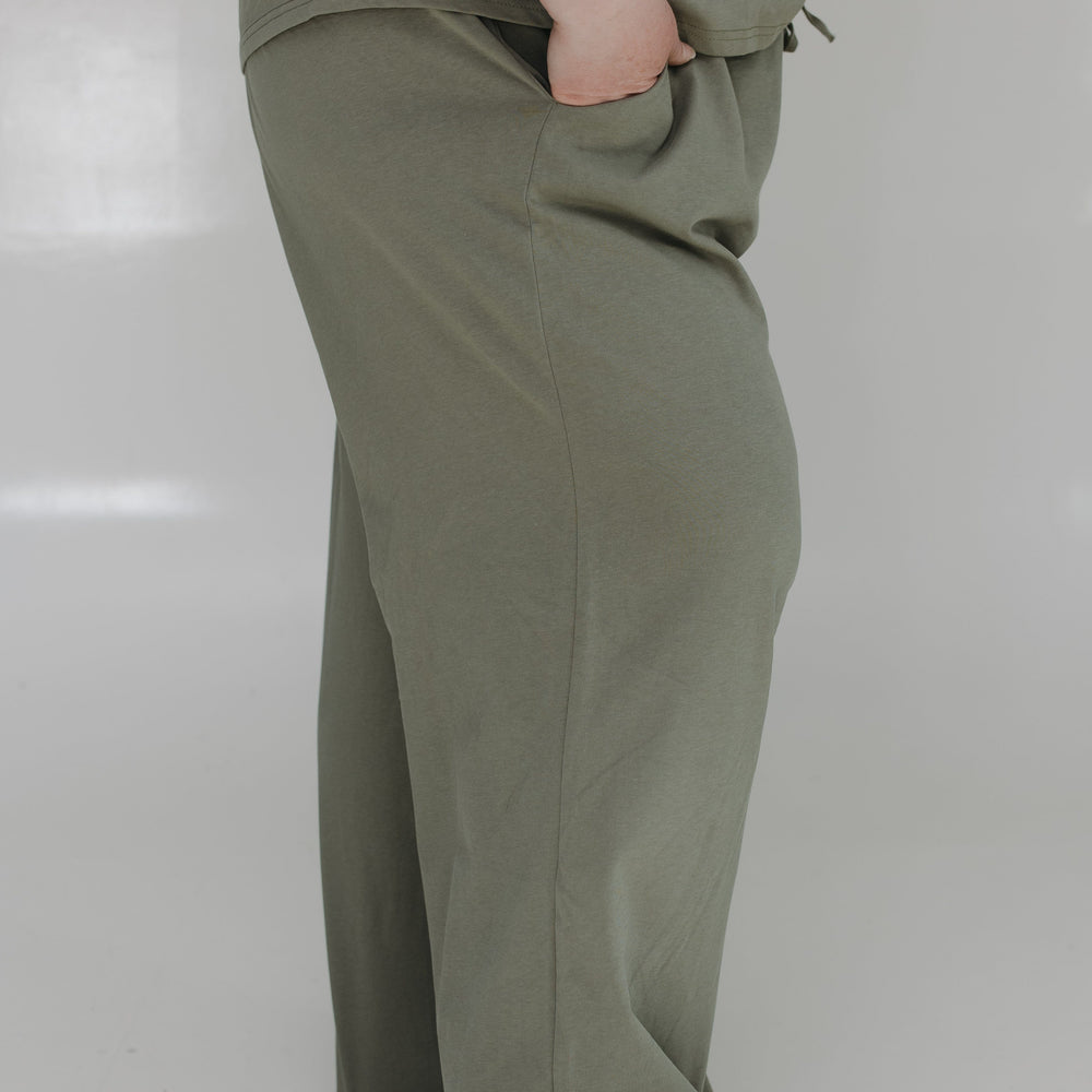 Person wearing olive green pants on a white background