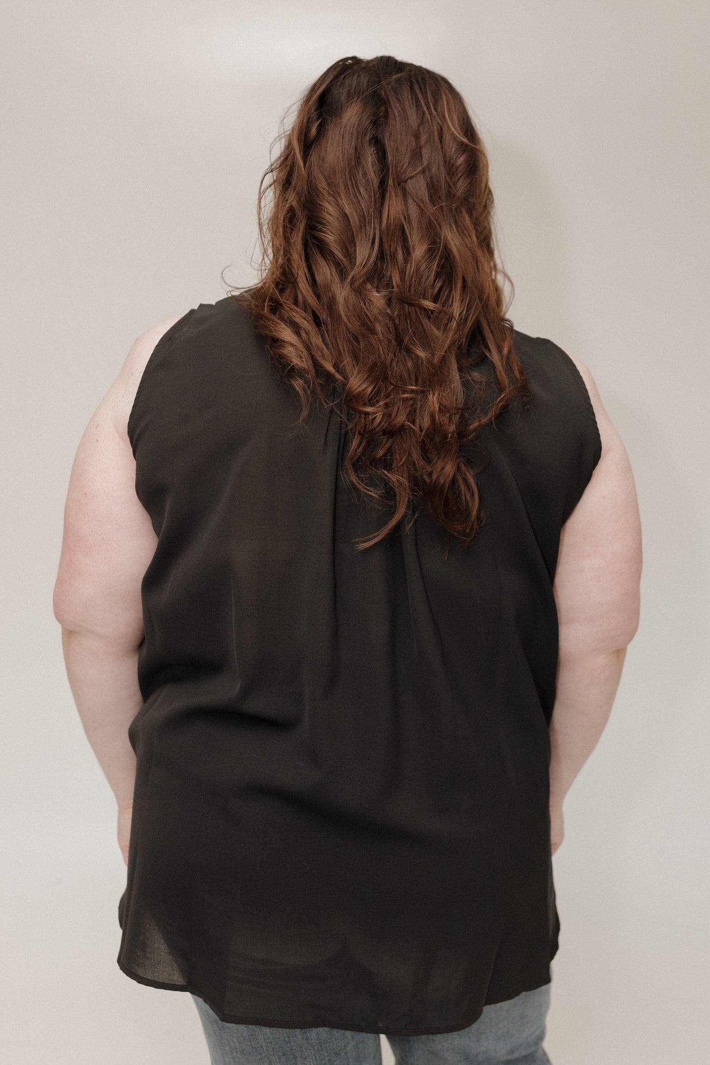 Person wearing a black sleeveless top against a plain background