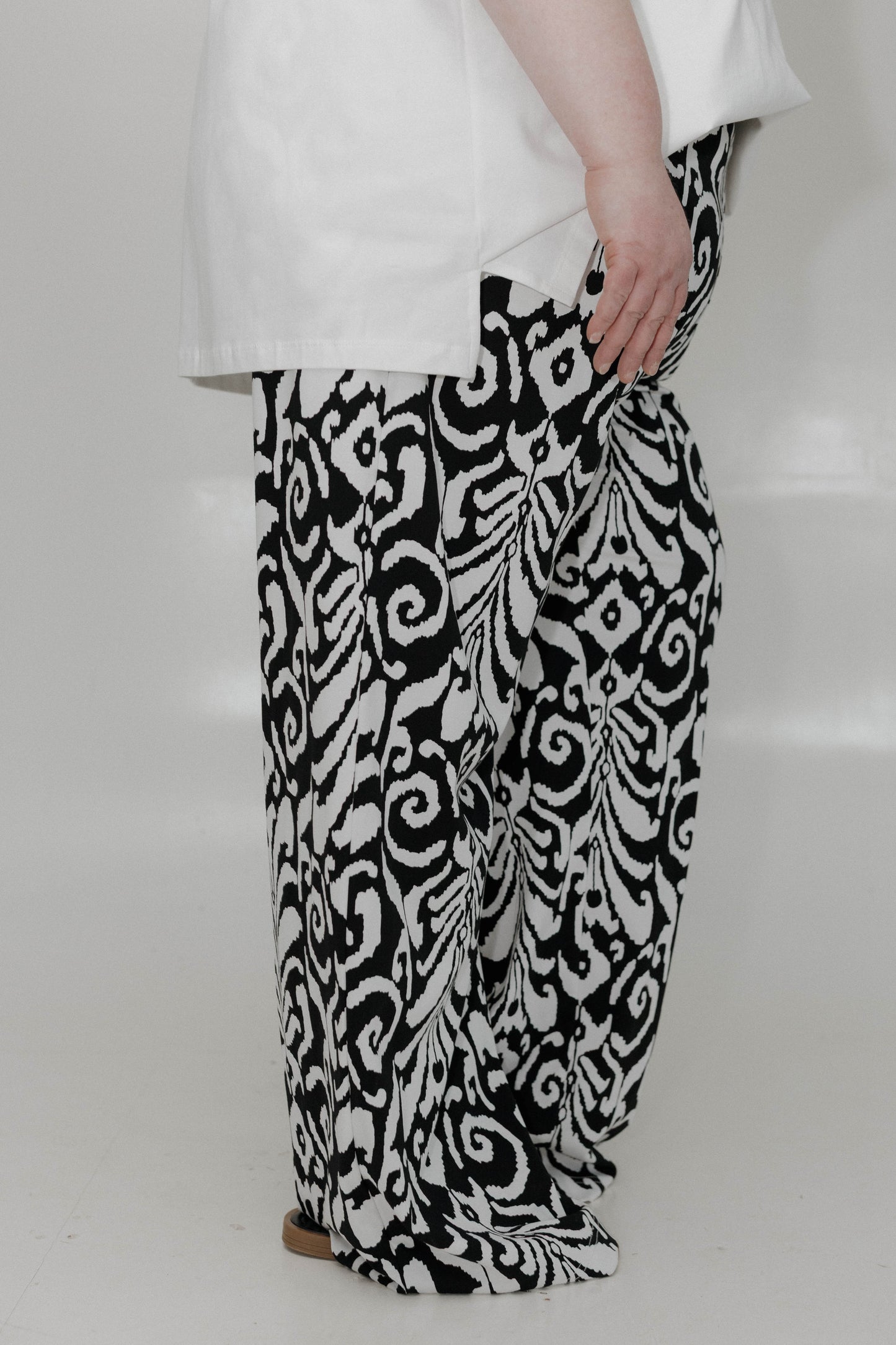 Person wearing black and white patterned pants on a plain background