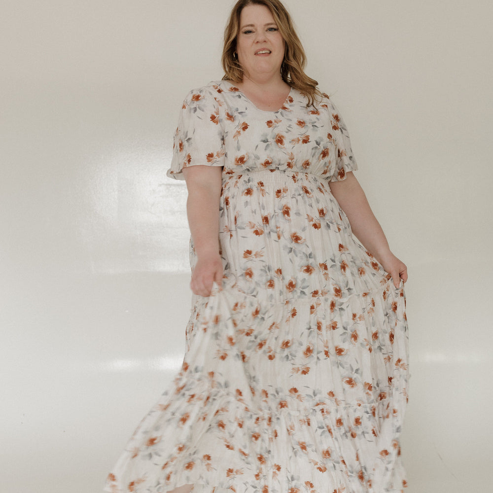 Woman wearing a floral dress standing against a white background