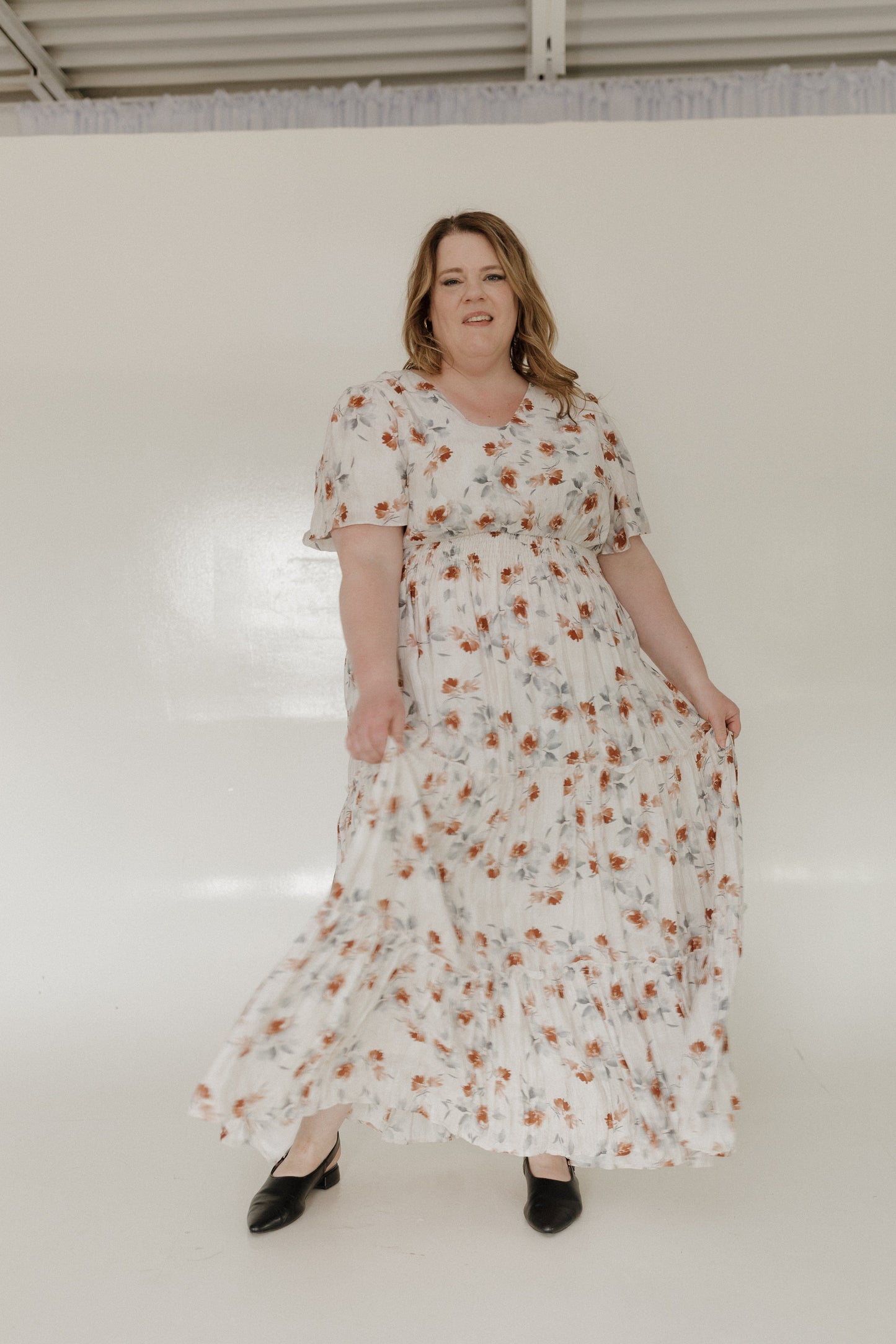 Woman wearing a floral dress standing against a white background