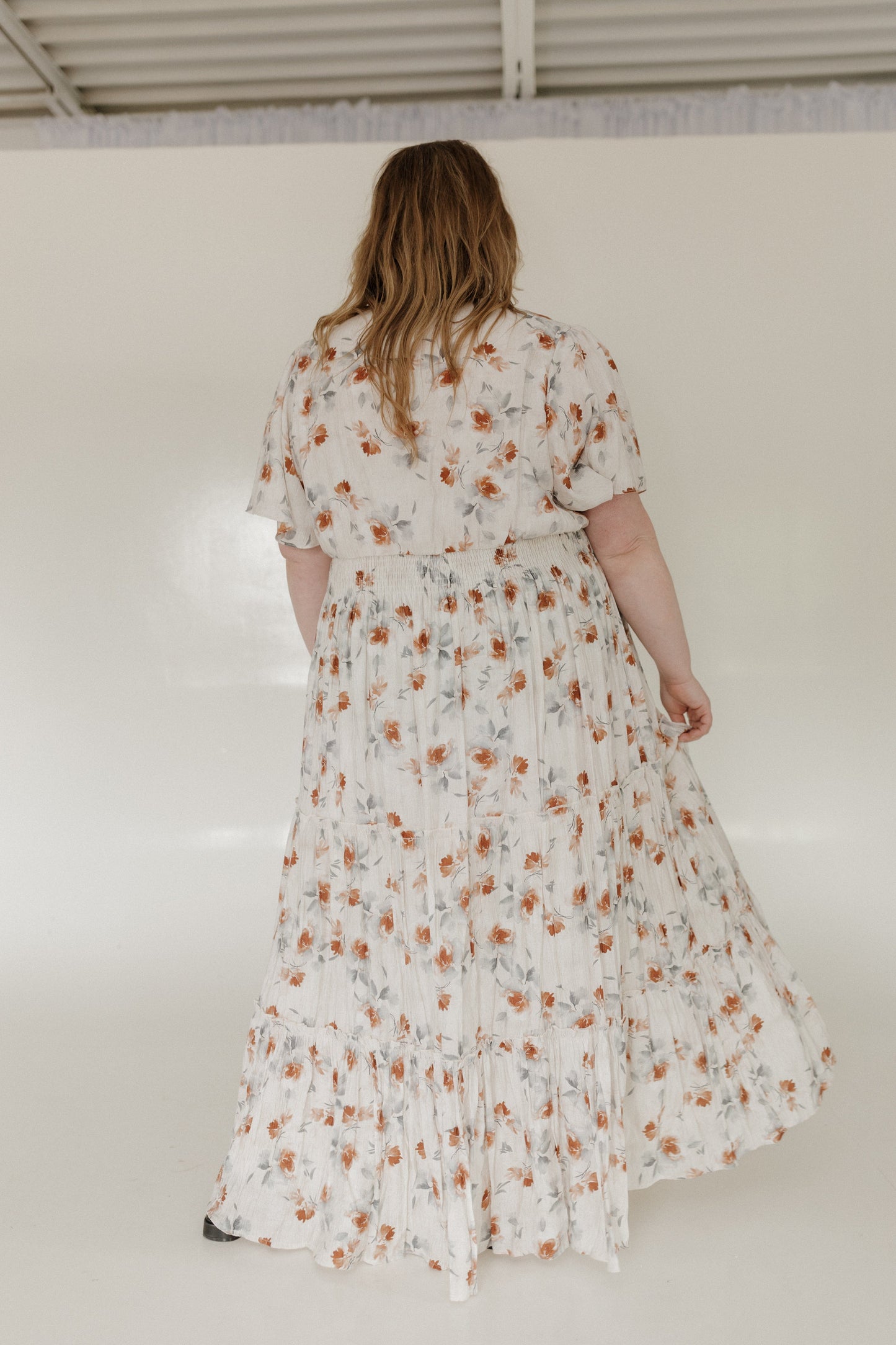 Woman wearing a floral dress against a white wall