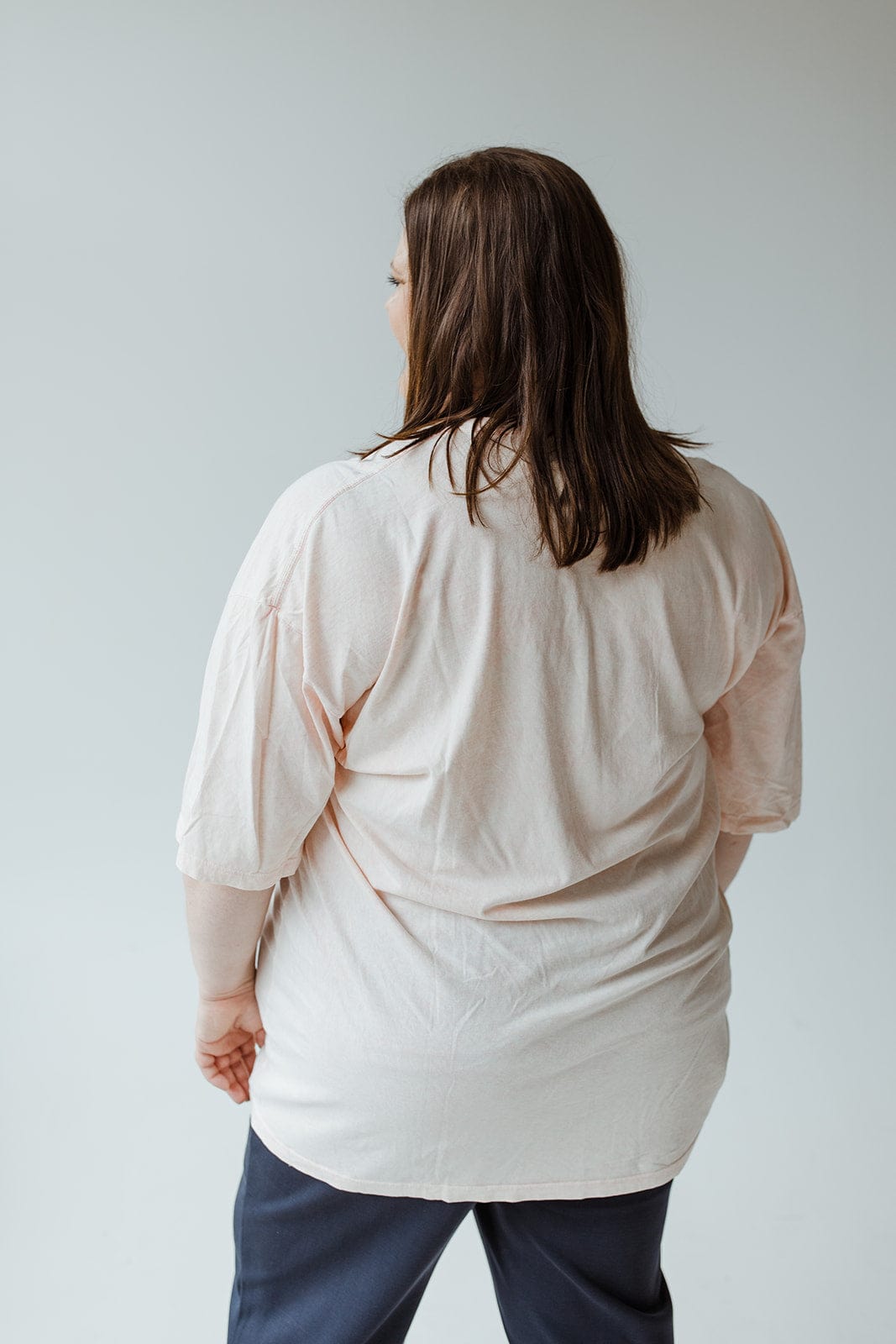 A person with shoulder-length hair is standing, facing away from the camera, wearing a 