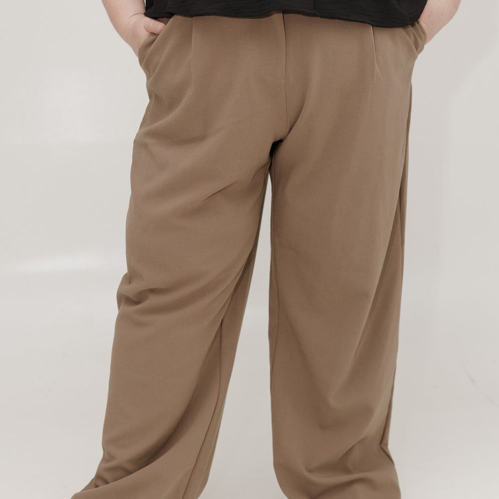 Person wearing brown wide-leg pants and a black top on a white background