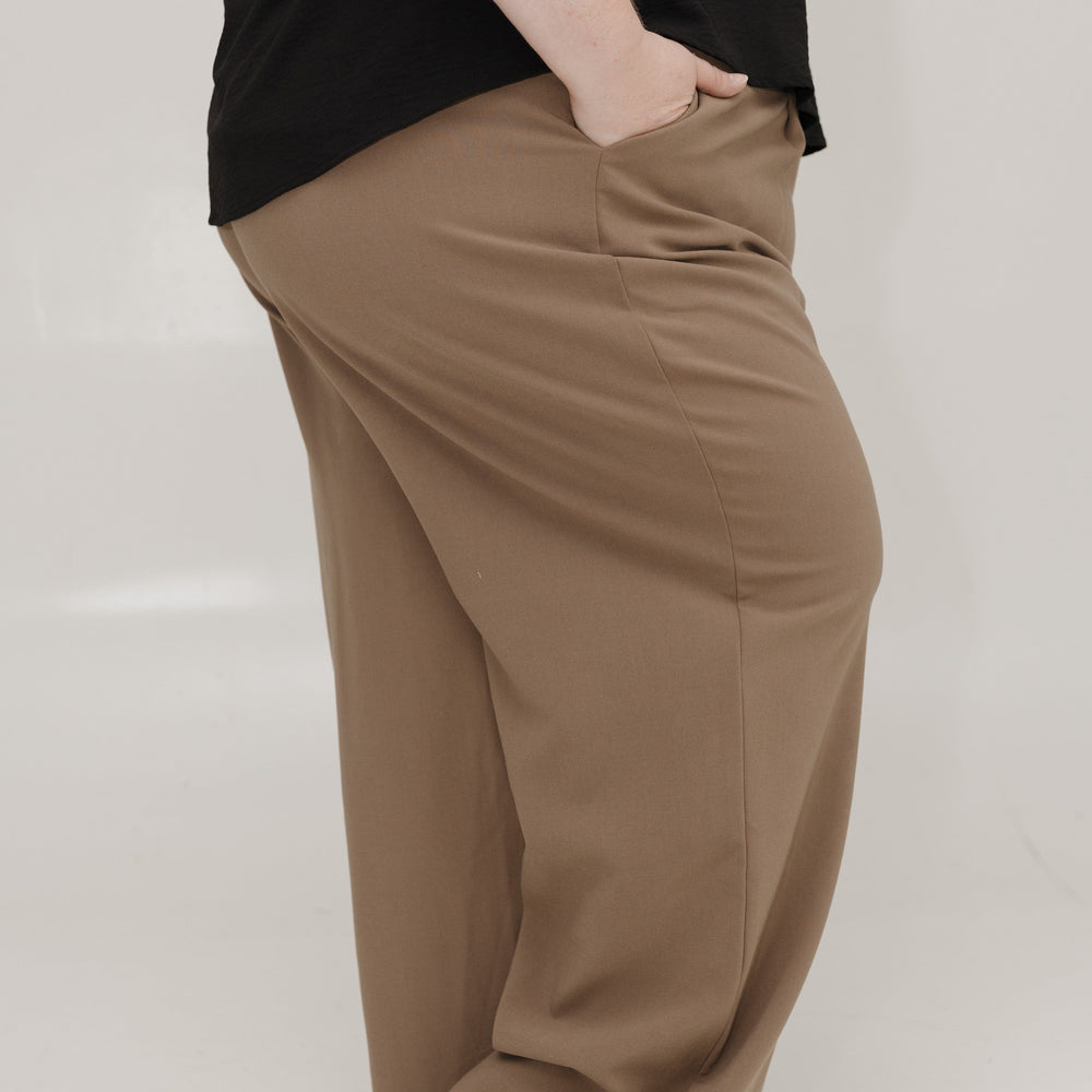 Person wearing brown wide-leg pants and a black top on a white background
