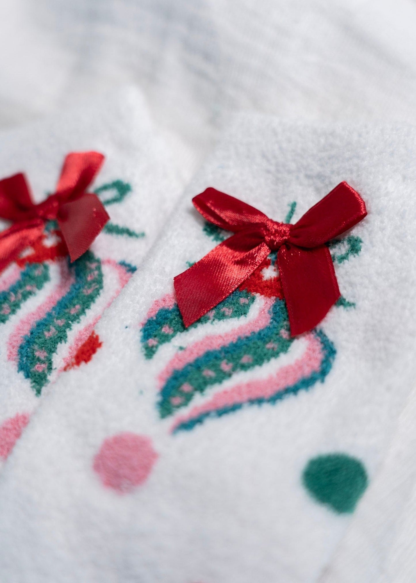 Close-up of a white fabric with red bows and colorful patterns on a white background