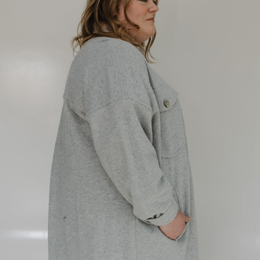 Person wearing a gray coat against a plain background