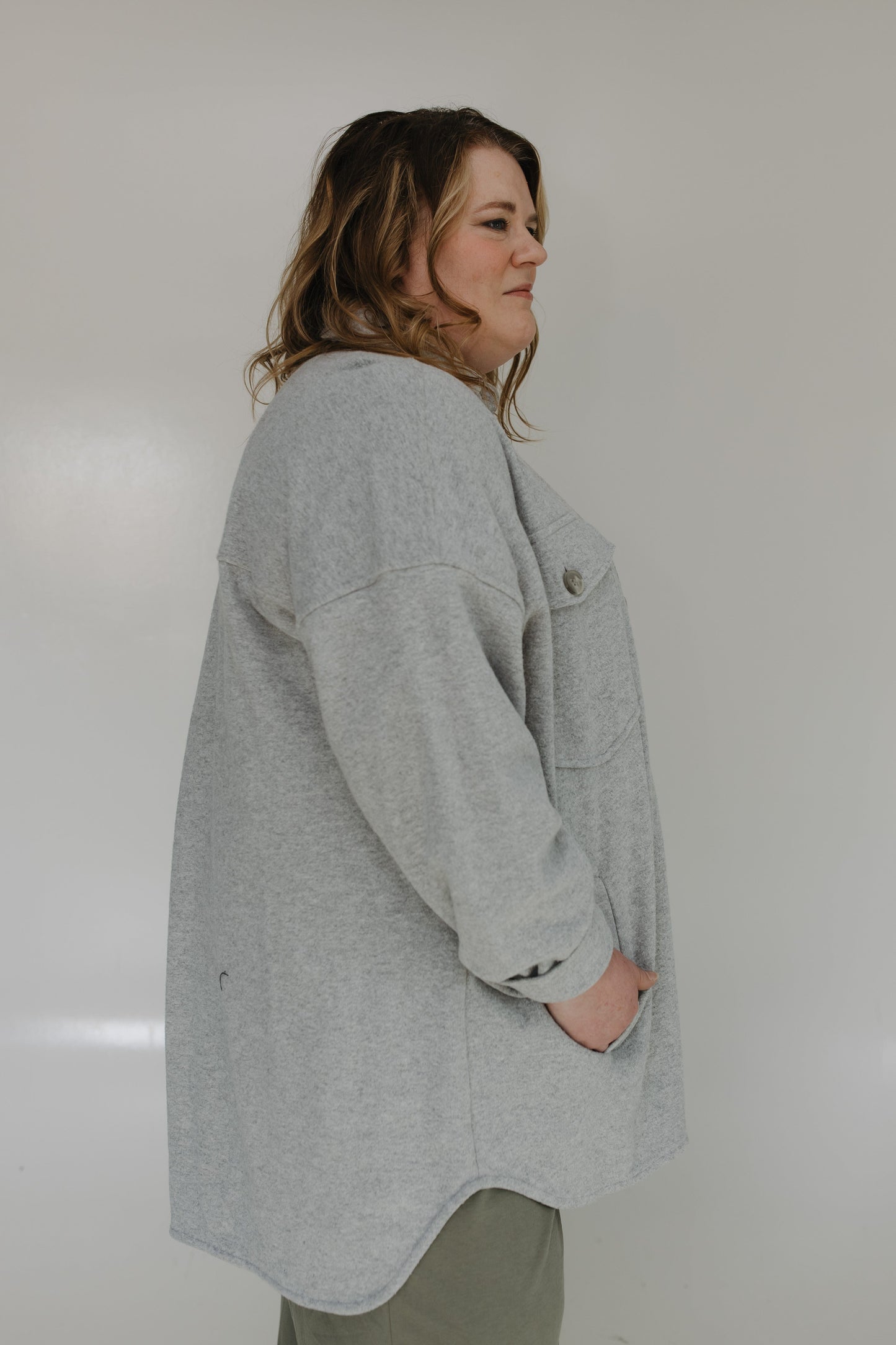 Person wearing a gray coat against a plain background