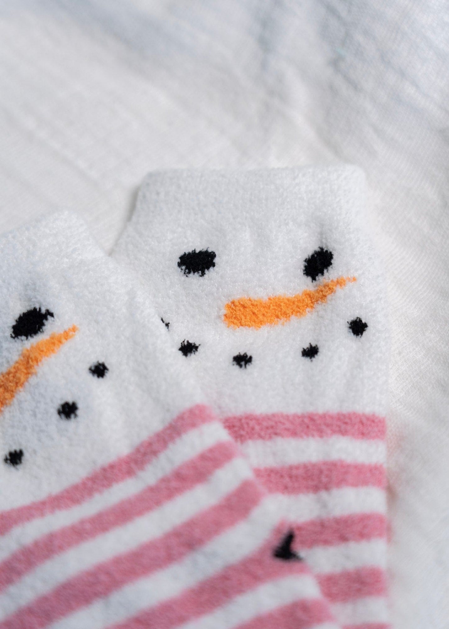 Close-up of a snowman-themed socks with pink and white stripes.