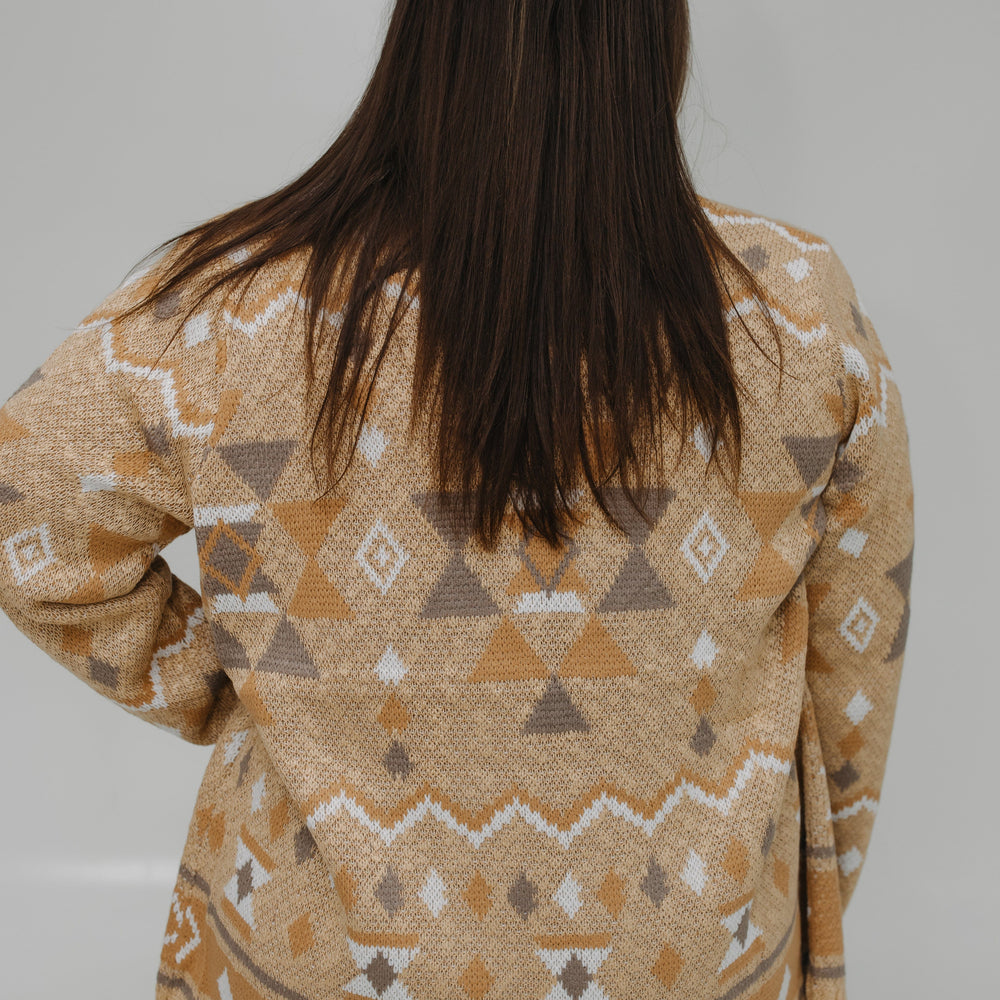 Person wearing a patterned beige sweater against a white background