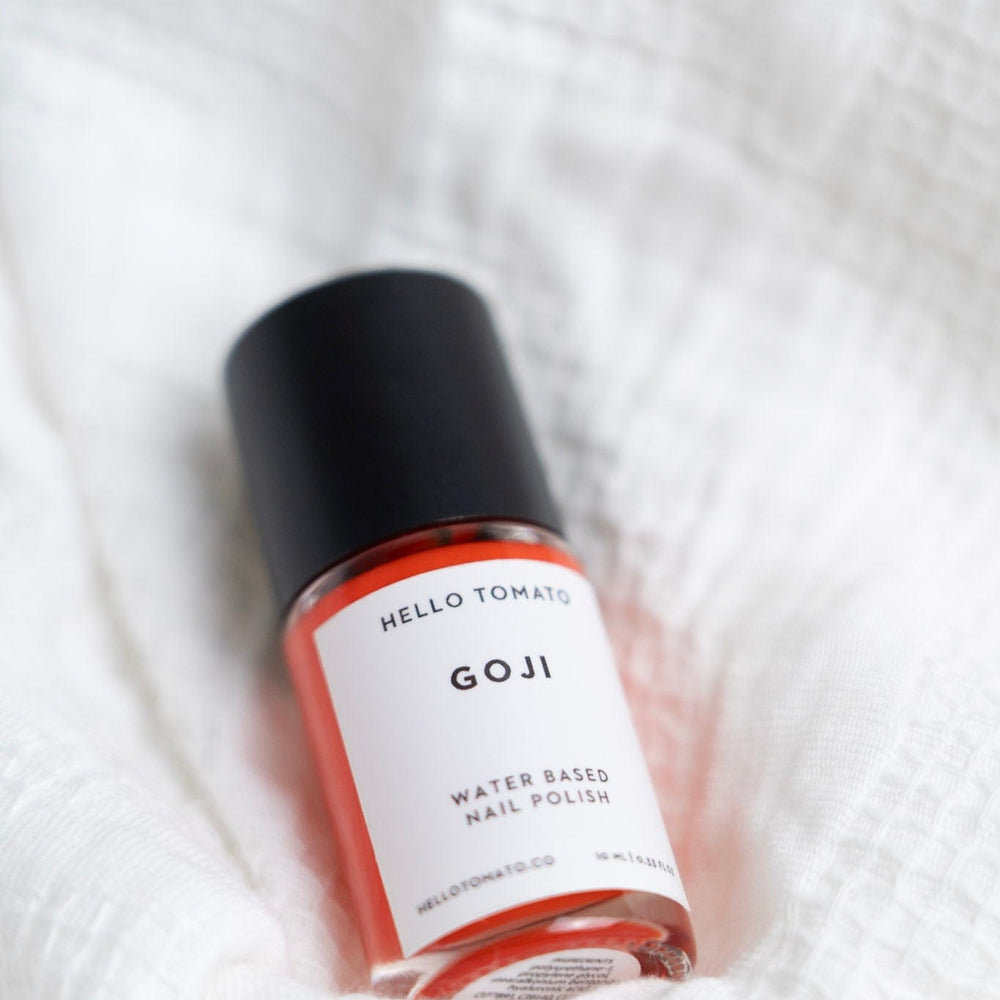 Bottle of GOJI water-based nail polish on a white textured background