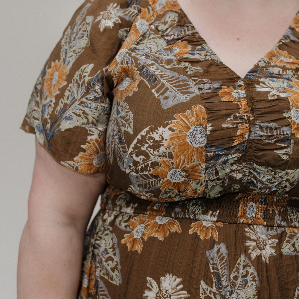 Brown floral dress worn by a person against a neutral background