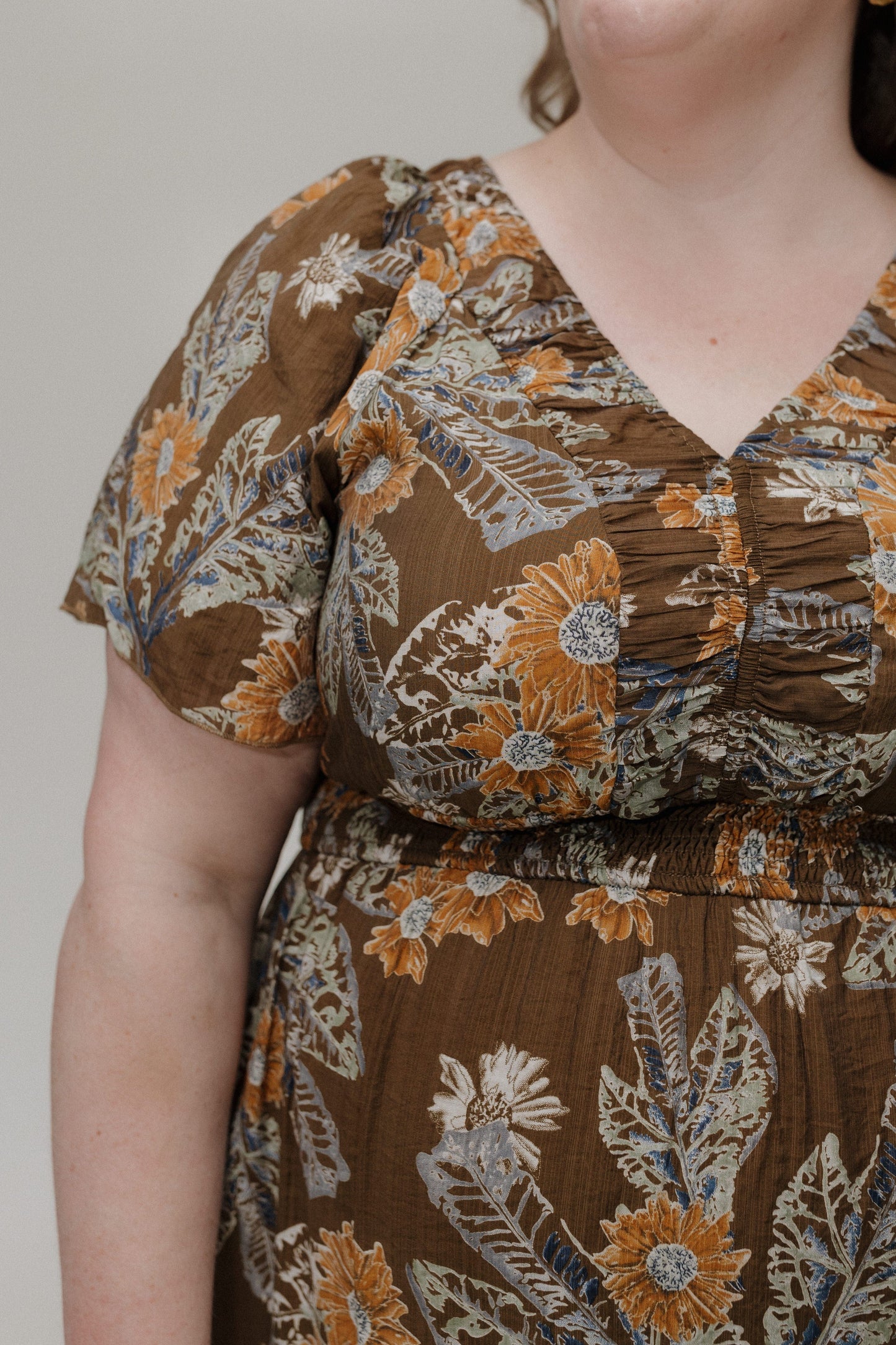 Brown floral dress worn by a person against a neutral background