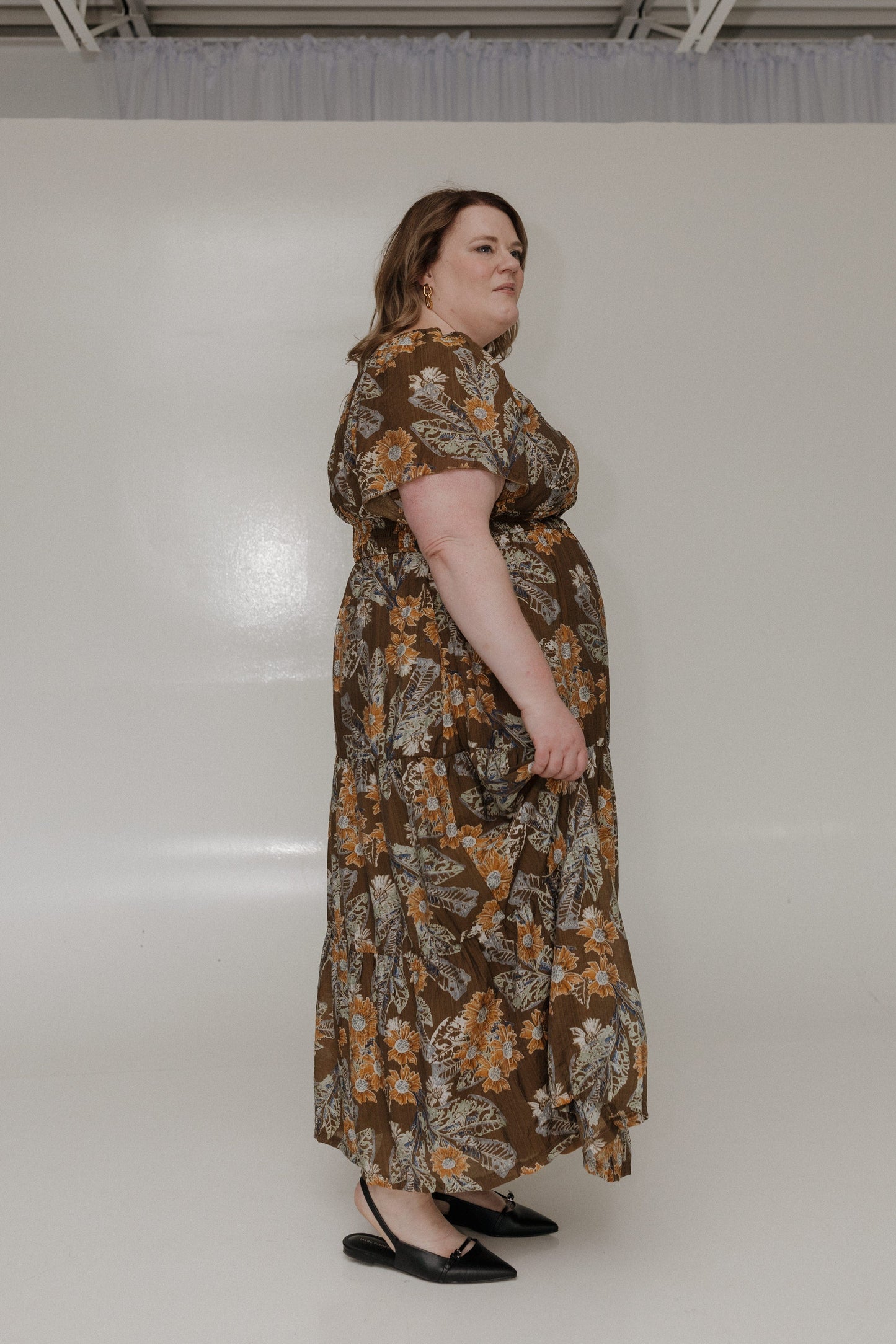 Woman wearing a floral dress standing against a plain background