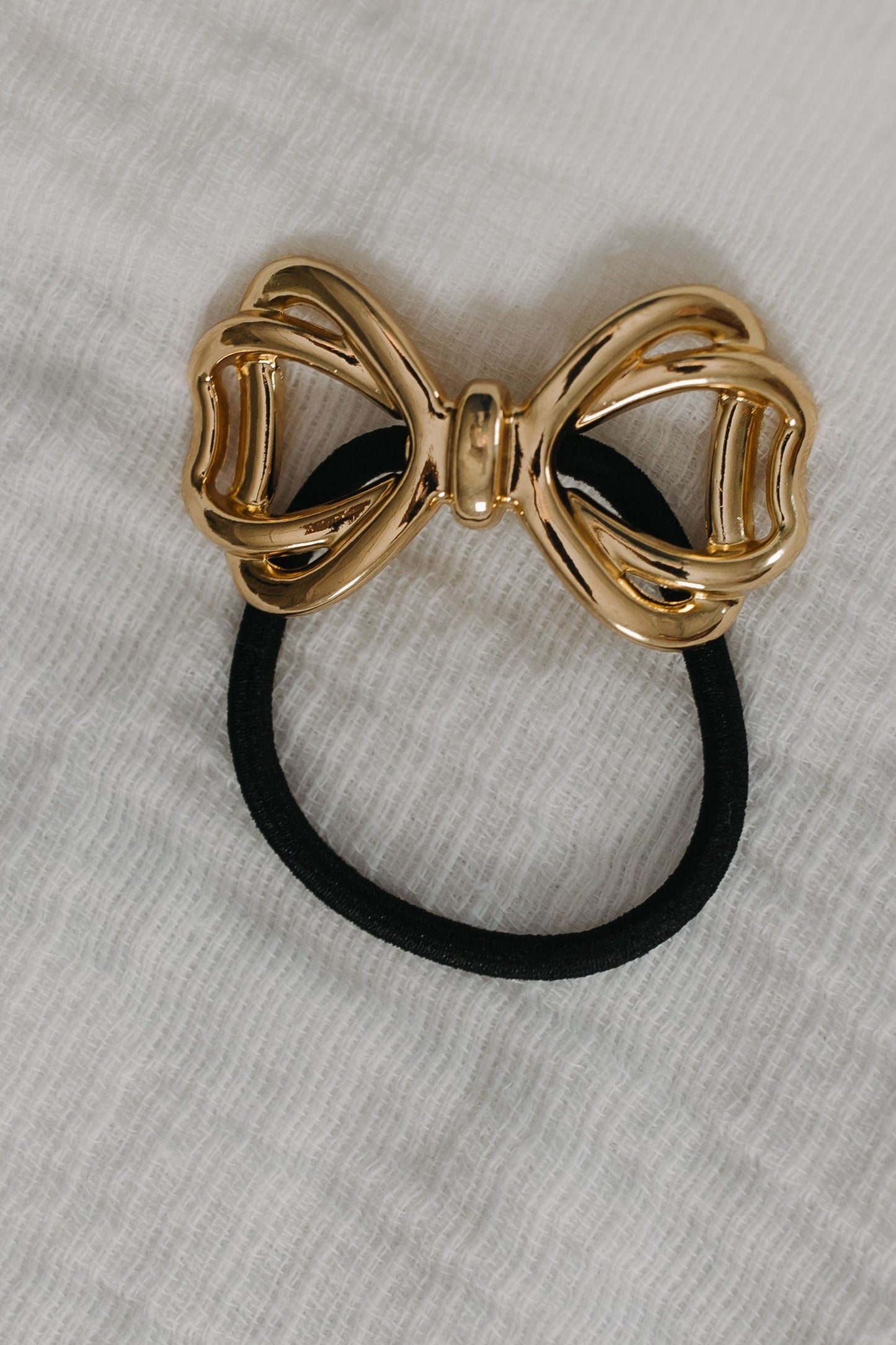 Gold bow-shaped hair tie on a gray background