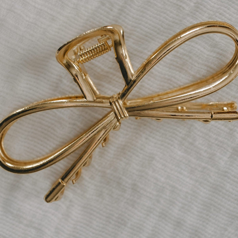 Gold bow-shaped hair clip on a light gray background