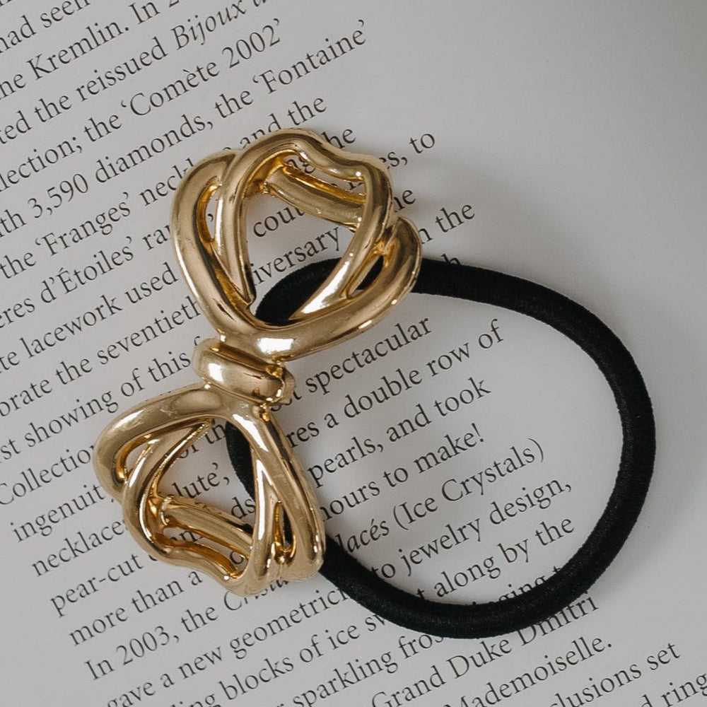 Gold bow-shaped hair tie on a book page
