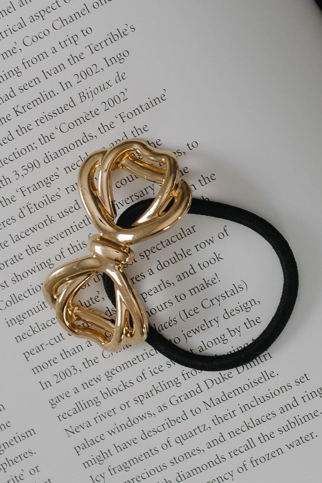 Gold bow-shaped hair tie on a book page