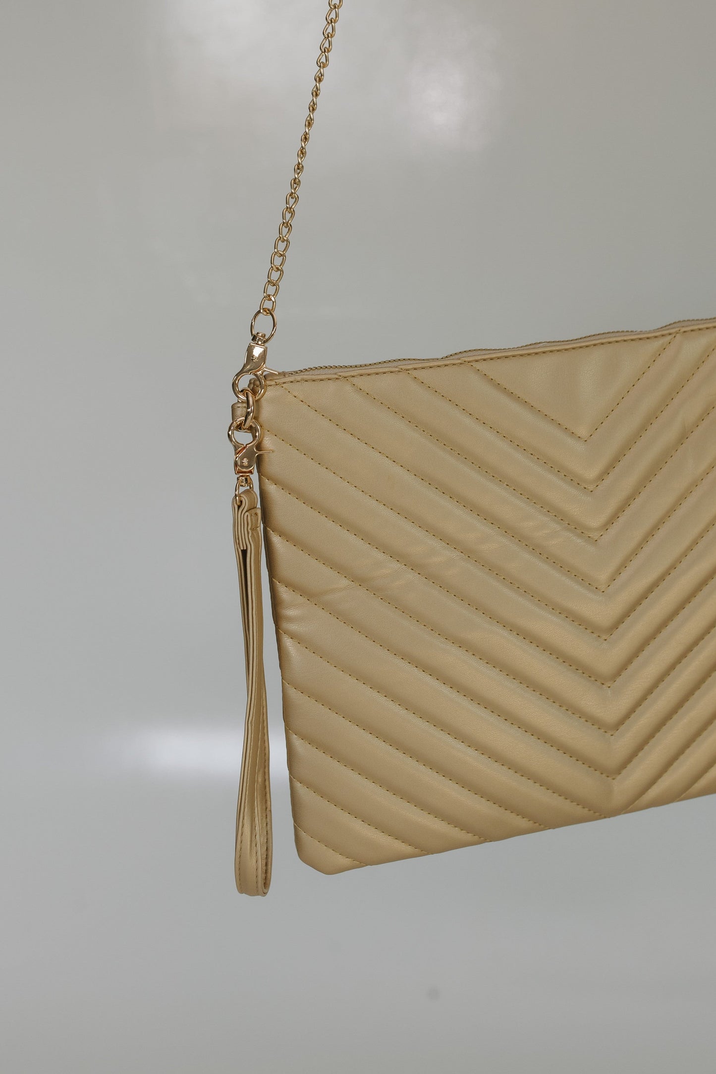 Beige clutch bag with a chain strap on a light gray background
