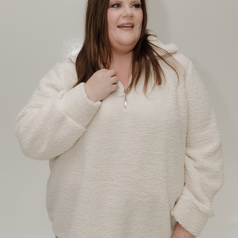 Woman wearing a beige sweater against a plain background