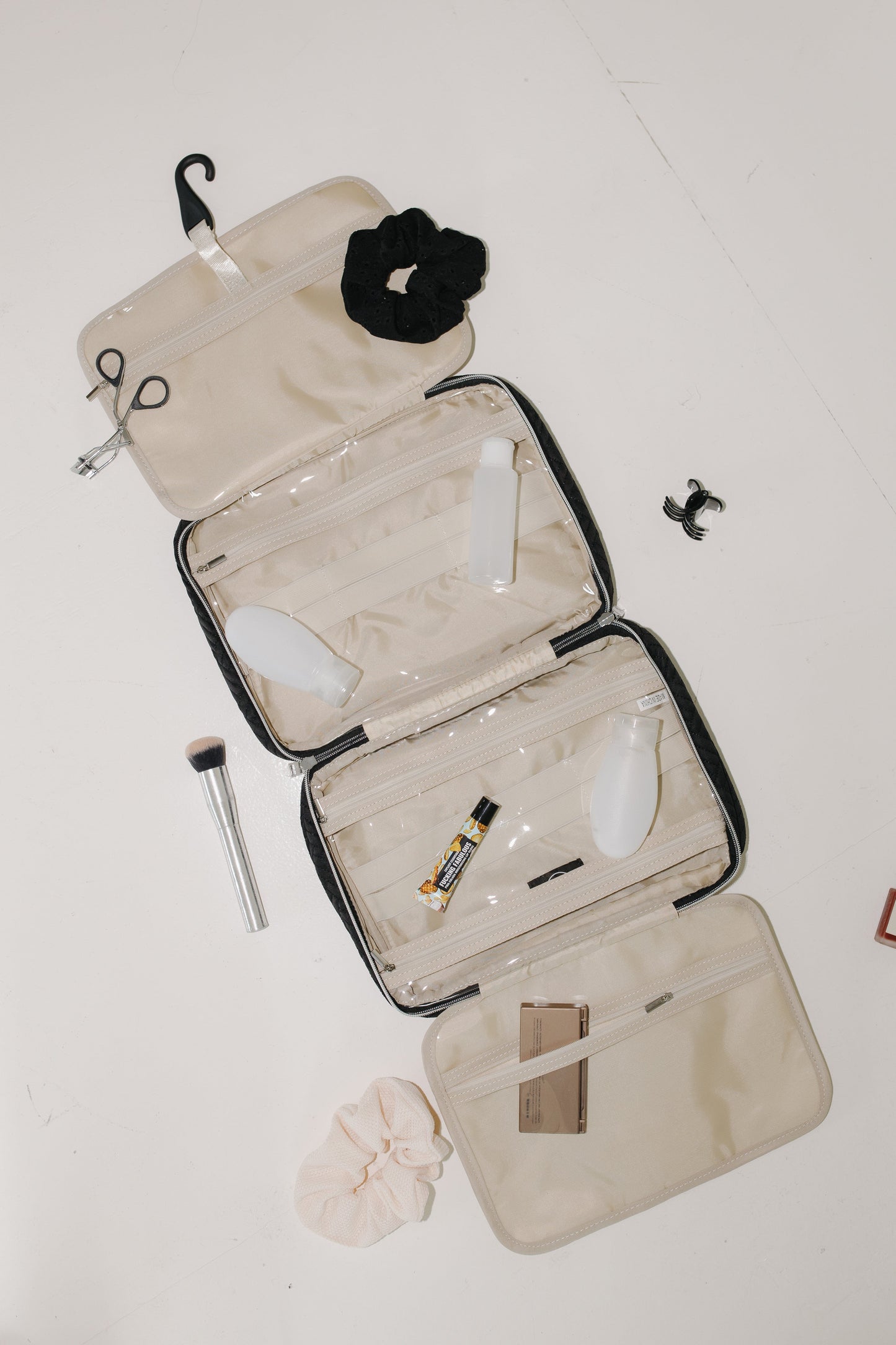 Open beige travel case with cosmetic items on a white background
