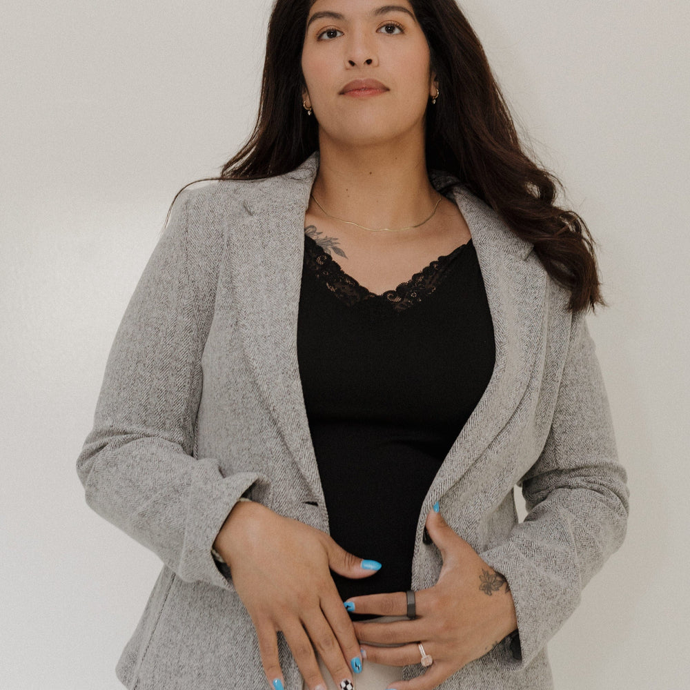 Woman wearing a gray blazer over a black top against a white background