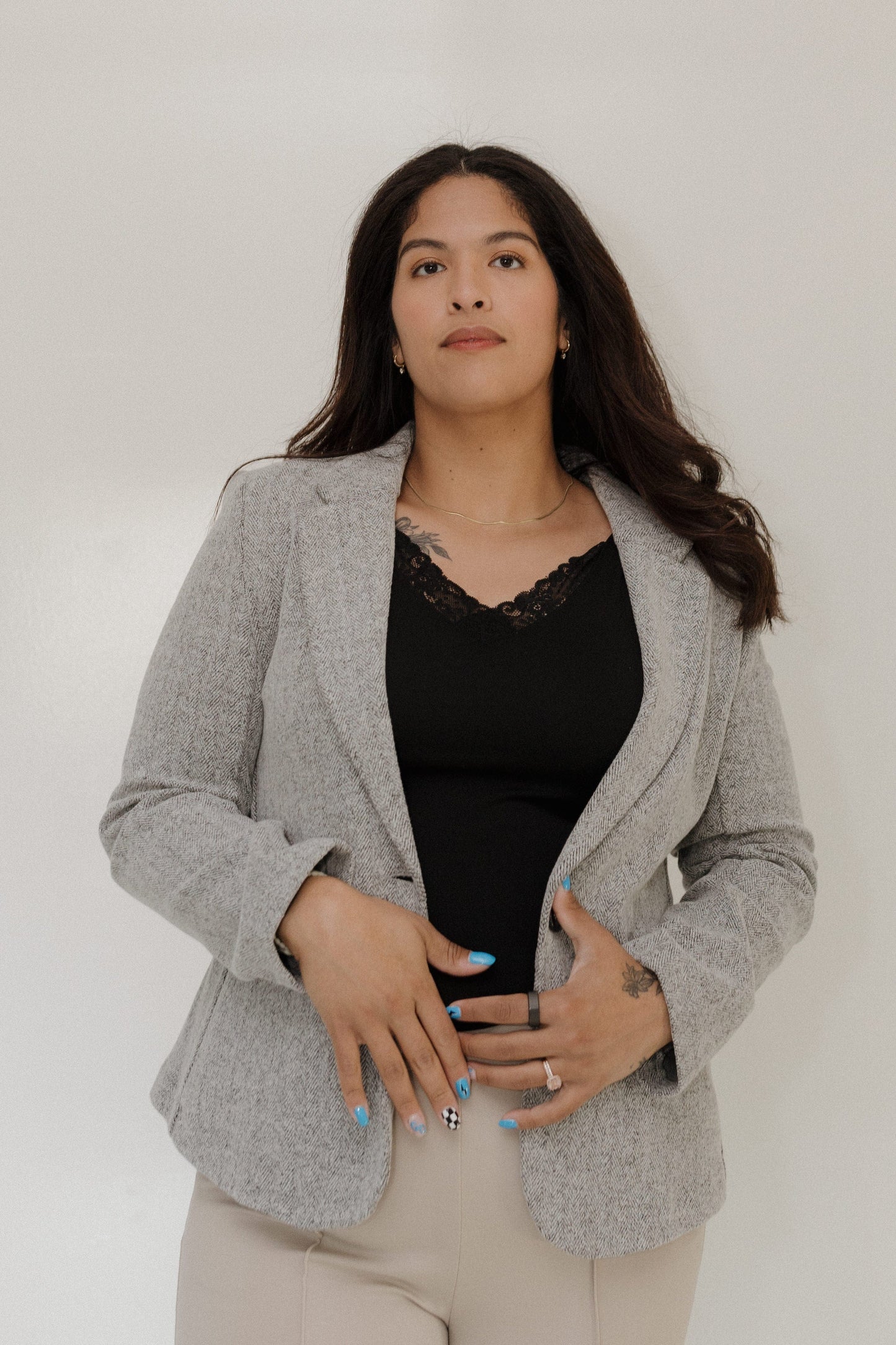 Woman wearing a gray blazer over a black top against a white background