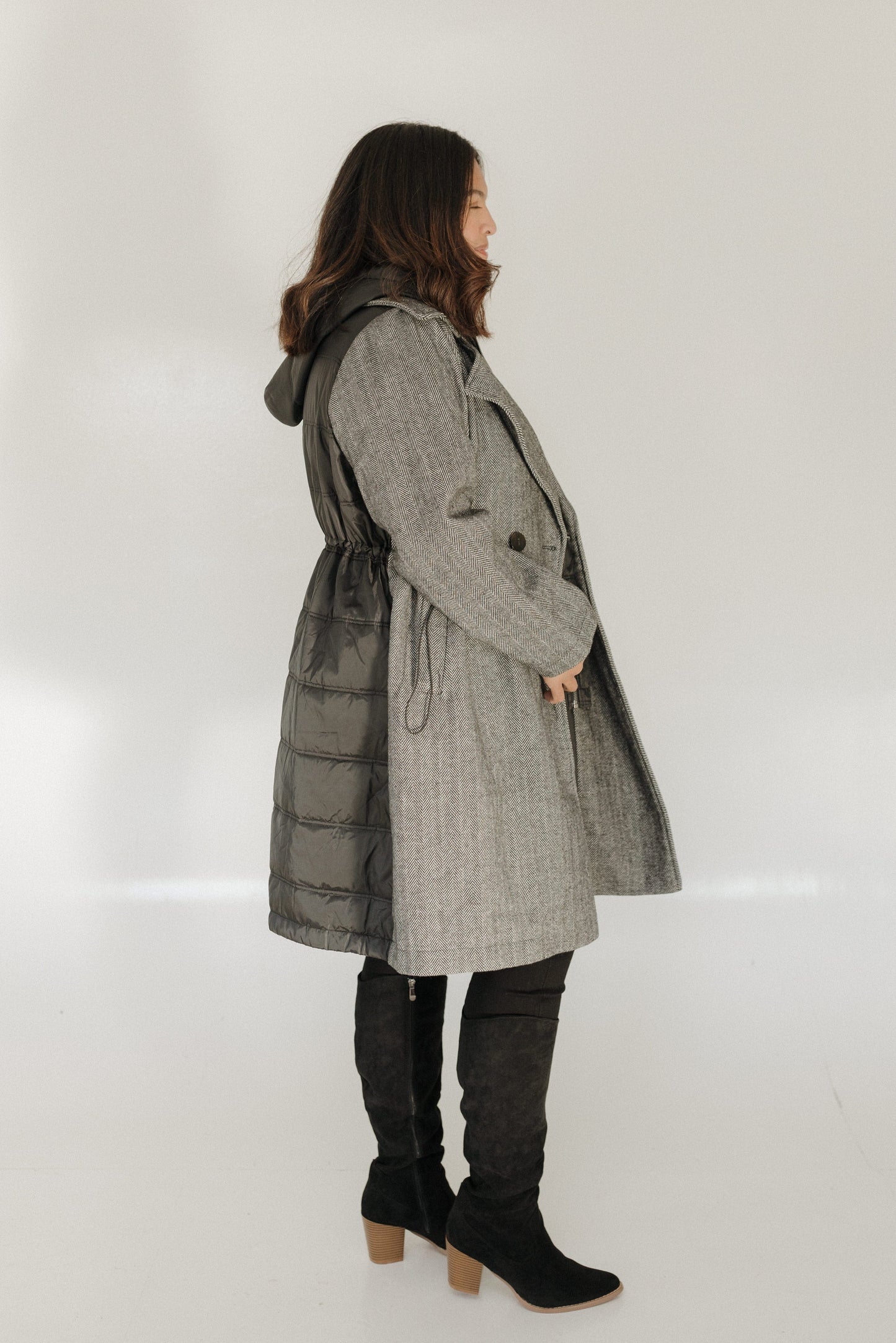 Person wearing a gray coat with a hood on a white background